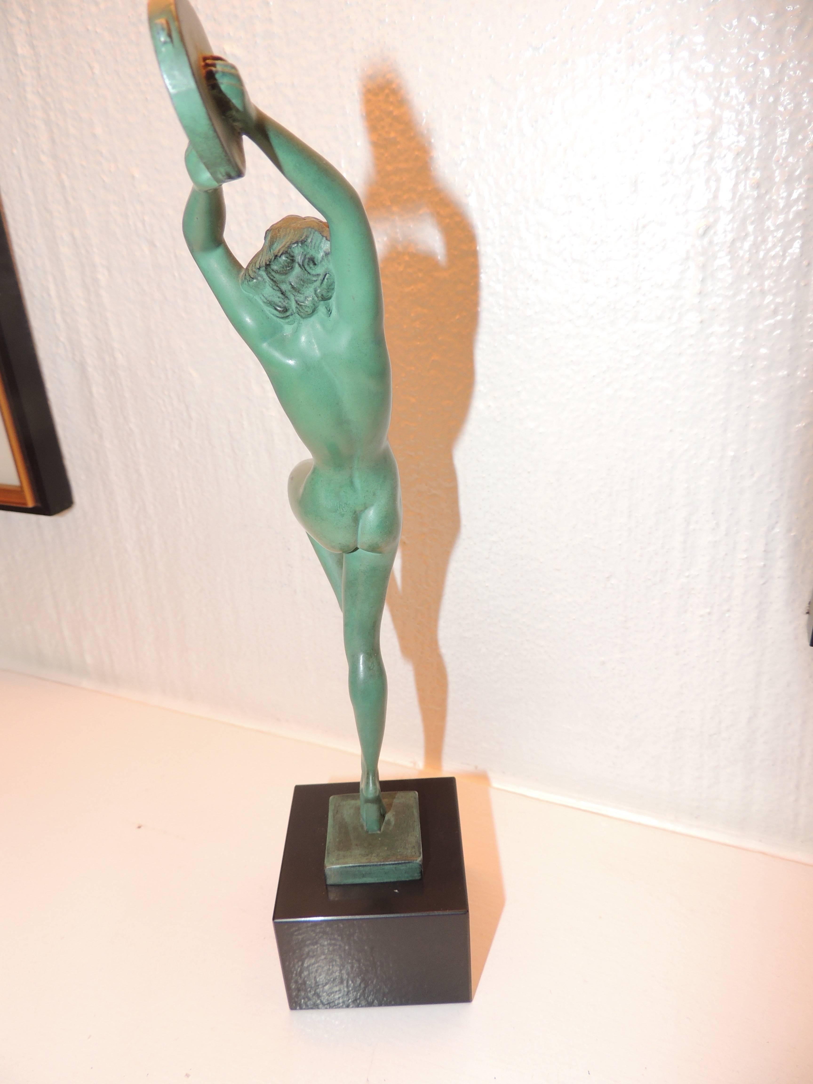 A petite Art Deco sculpture created in the early 1930s, sometimes referred to by the name “Esmeralda”. This piece is both athletic and feminine in its bold pose holding a tambourine high above her head. The finish is patina green, mounted on a