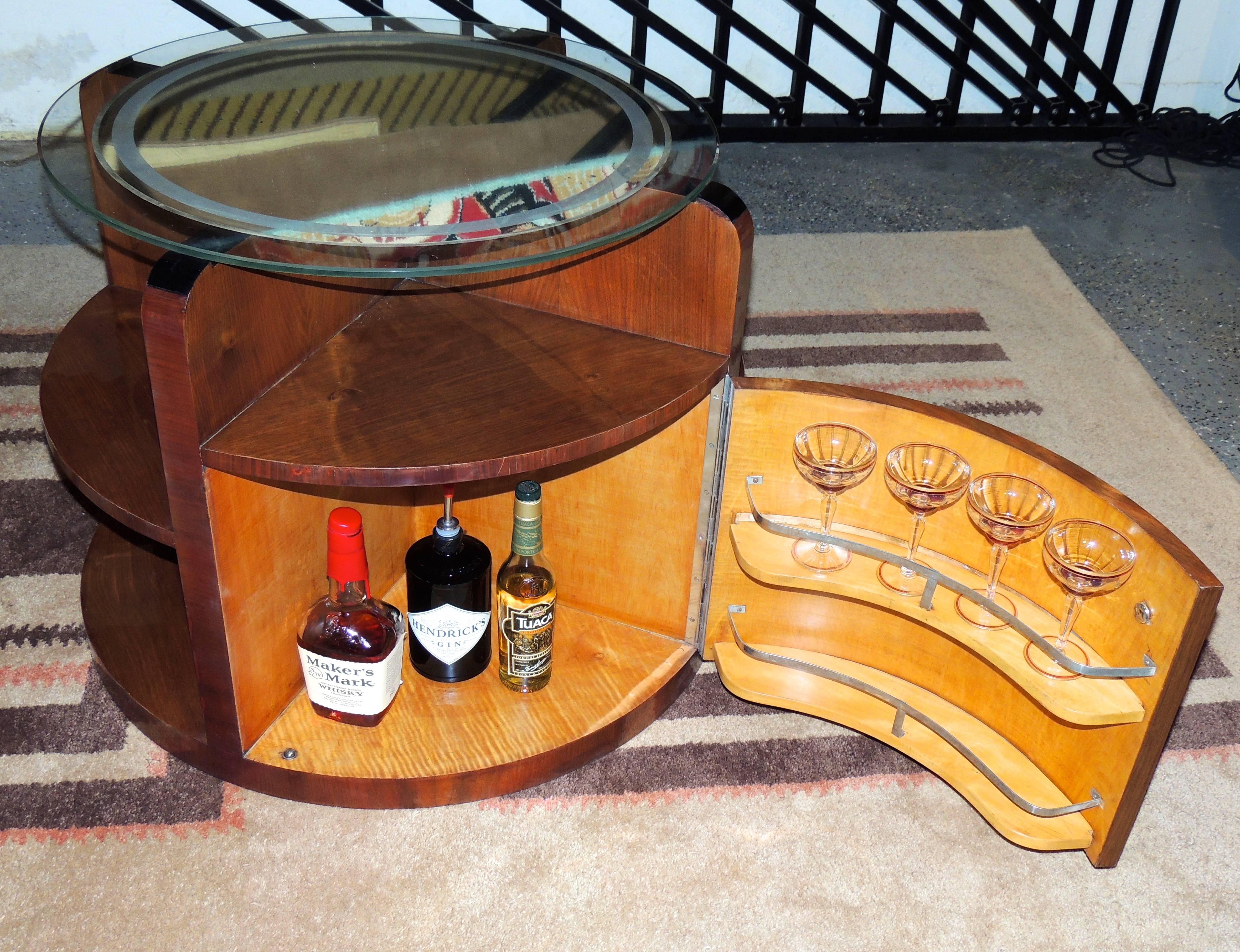 A sleek round table with hidden bar cabinet was “all the rage” in the Art Deco Era. In this piece, a beautiful walnut cabinet has two compartments to hold bottles and glasses, nice shelving on the exterior for display and an etched round mirror as