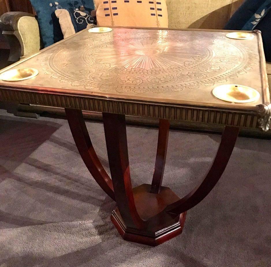 Unique brass topped game table or side table with elaborate hand tooled pattern on a graceful wooden base. The built in removable trays at each of the four corners can hold gambling chips (or potato chips!) or can be used as ashtrays. With a