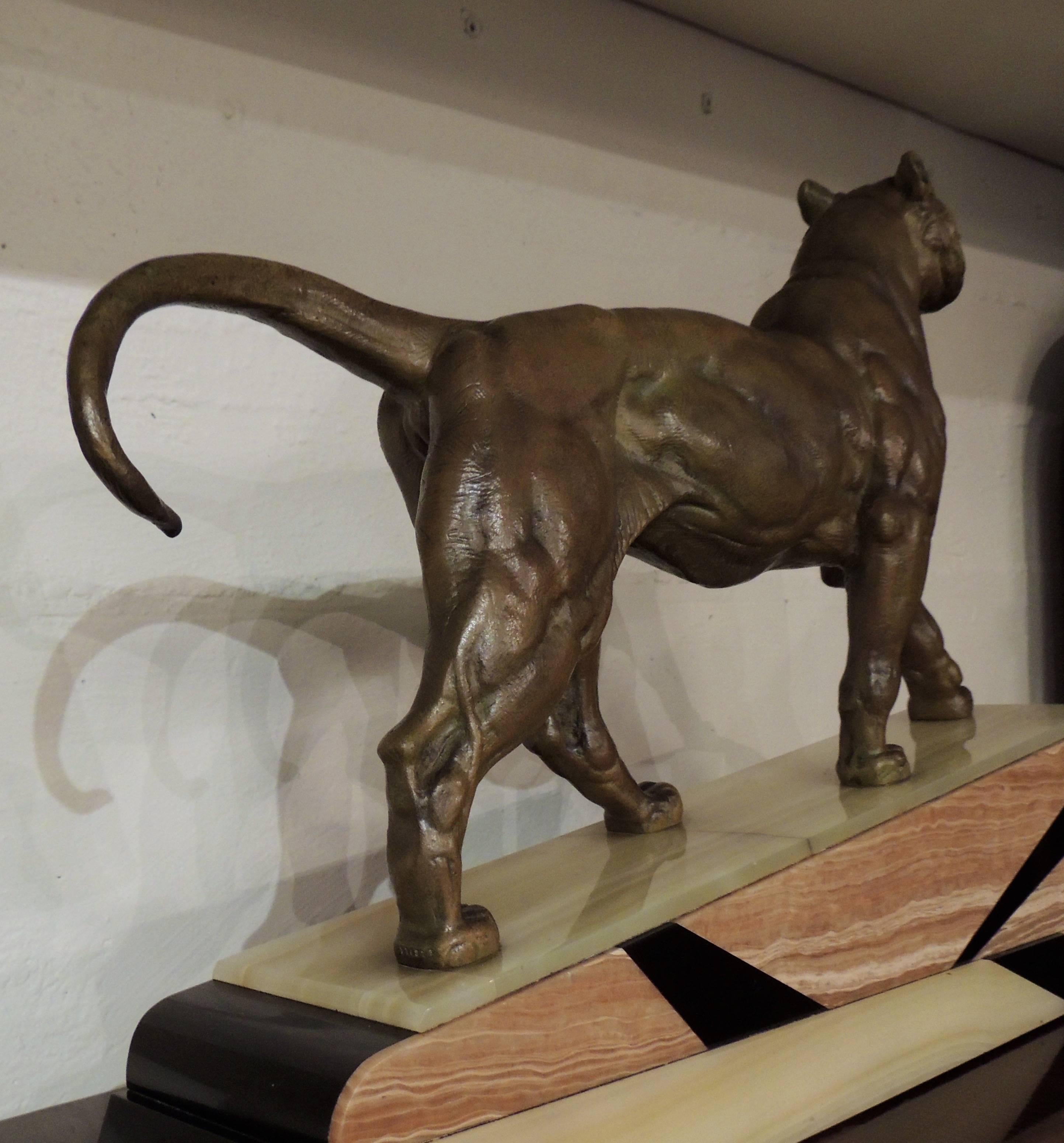 An Art Deco era bronze statue of a lion with a great marble base of three tones inlaid in geometric shapes. The lion is powerfully rendered, its expression and musculature well defined.

Throughout history, the Lion has been known as the “king of