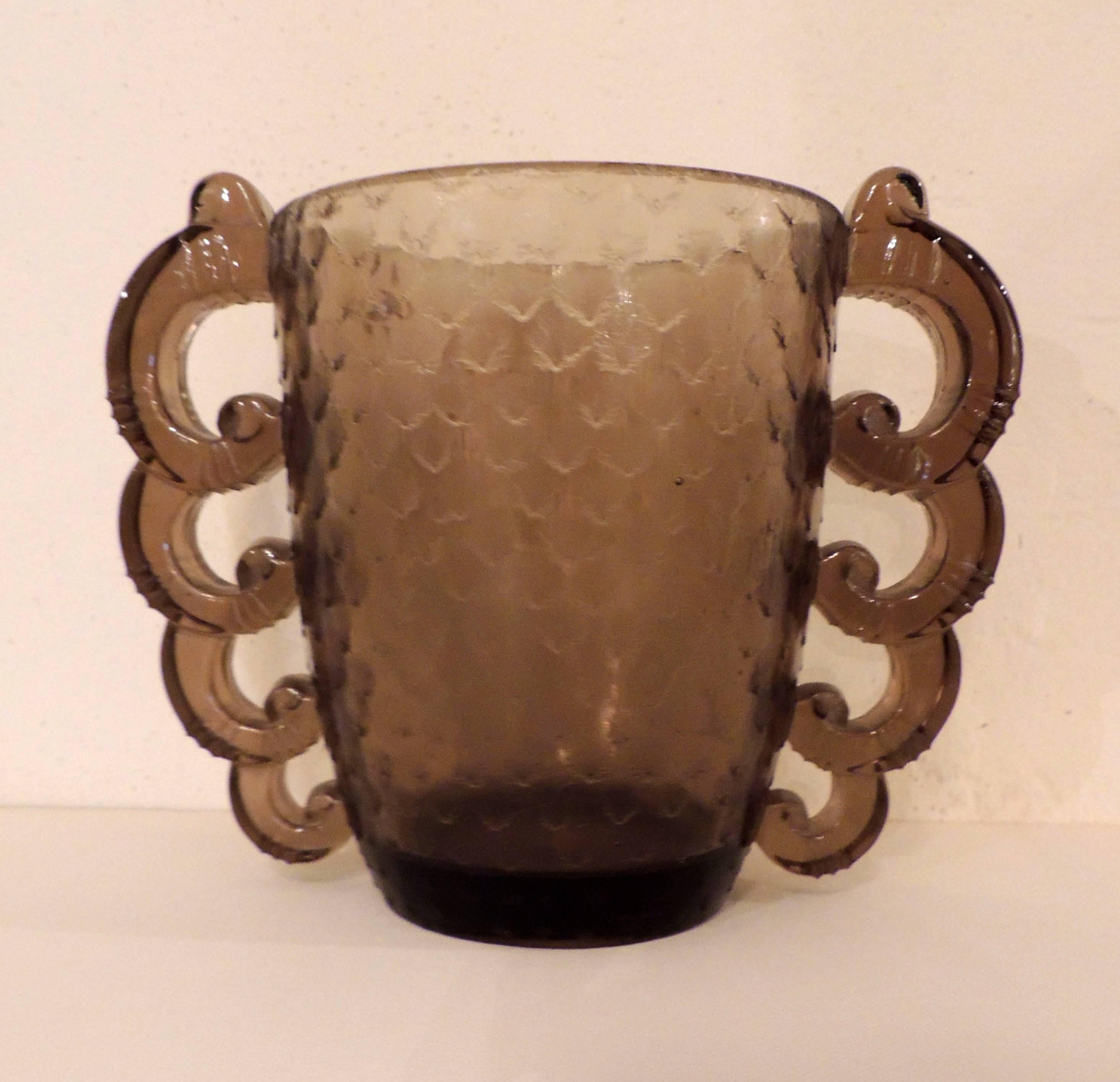 A French Art Deco glass vase in a smoky “topaz” tone with a great textured surface and those dramatic scalloped “handles” that echo some of the shapes created by the glass masters such as Lalique. This example was made for Daum by Pierre D’Avesn.
