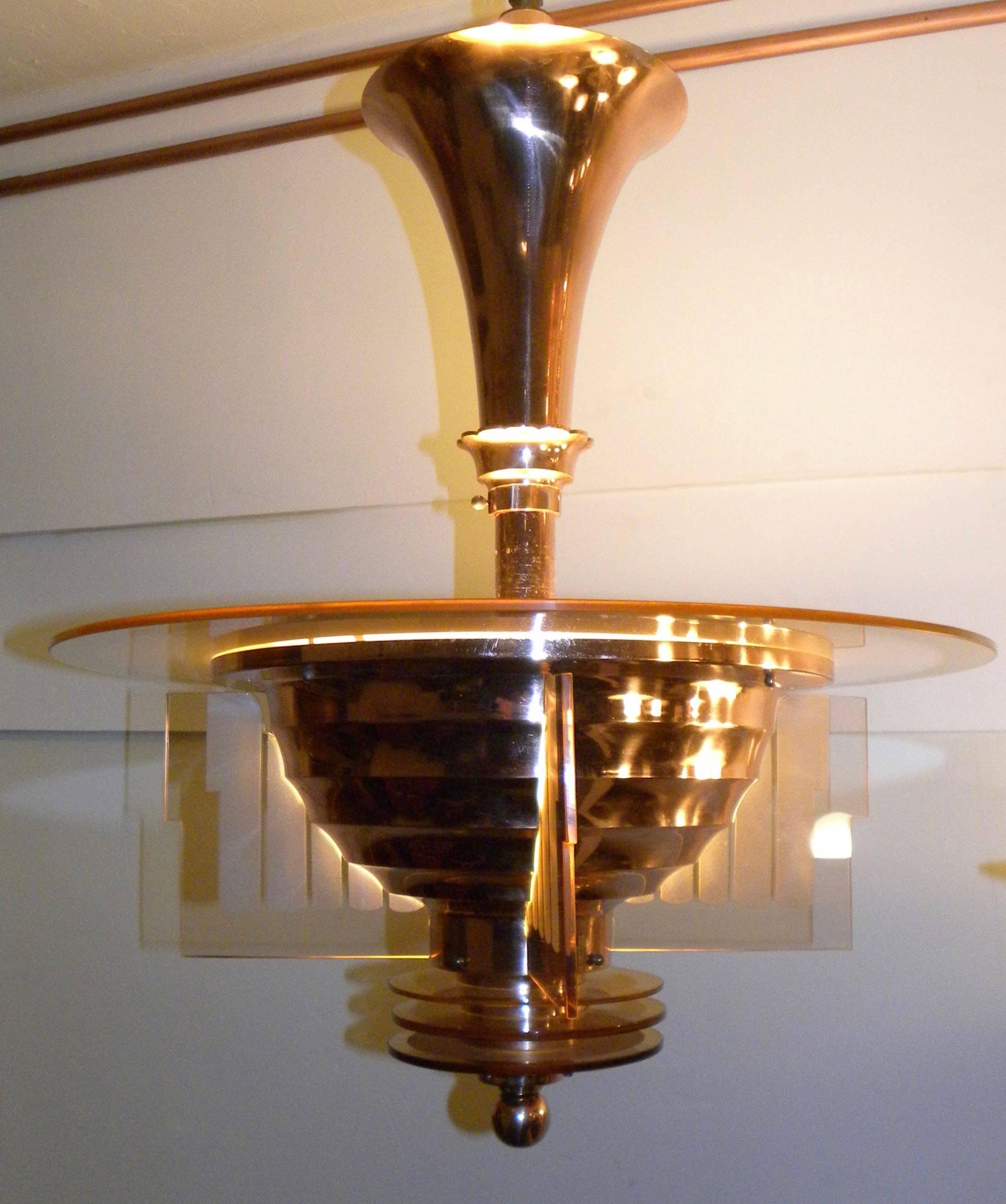 Spectaculaire:: dynamique et épuré:: ce luminaire d'Henri Petitot est l'un des plus beaux exemples de l'Art Déco français. Façonné dans un cuivre riche qui se marie magnifiquement avec le verre pêche gravé et avec les 