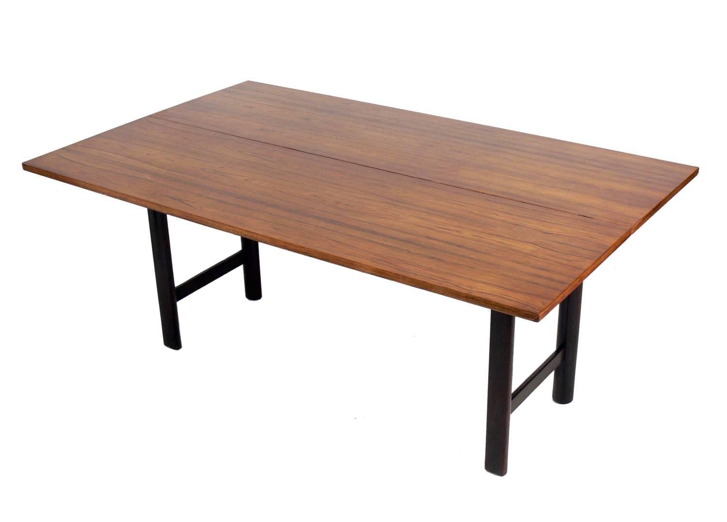 Ingenious rosewood console or dining table, designed by Edward Wormley for Dunbar, circa 1950s. This clean lined console table quickly and easily opens to a full size dining table. With a simple flip and slide, it goes from 20
