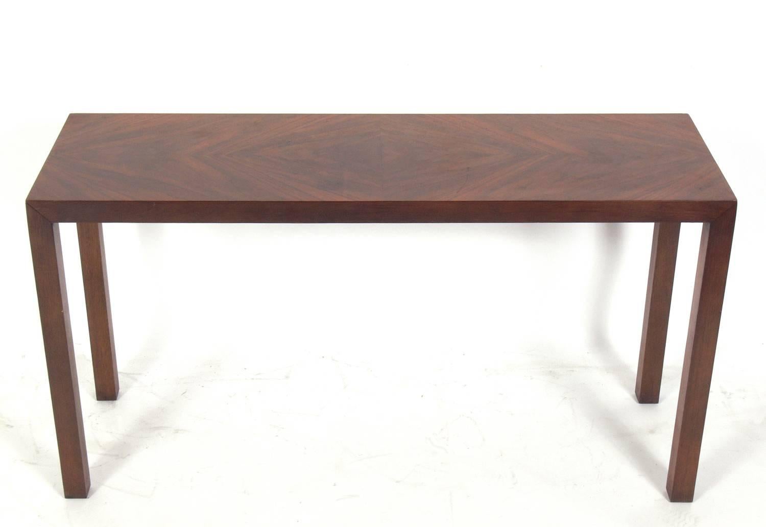 Clean lined rosewood console table, American, circa 1960s. This piece is a versatile size and can be used as a console or sofa table, vanity, bar, or desk. Clean lined design with beautifully grained rosewood.