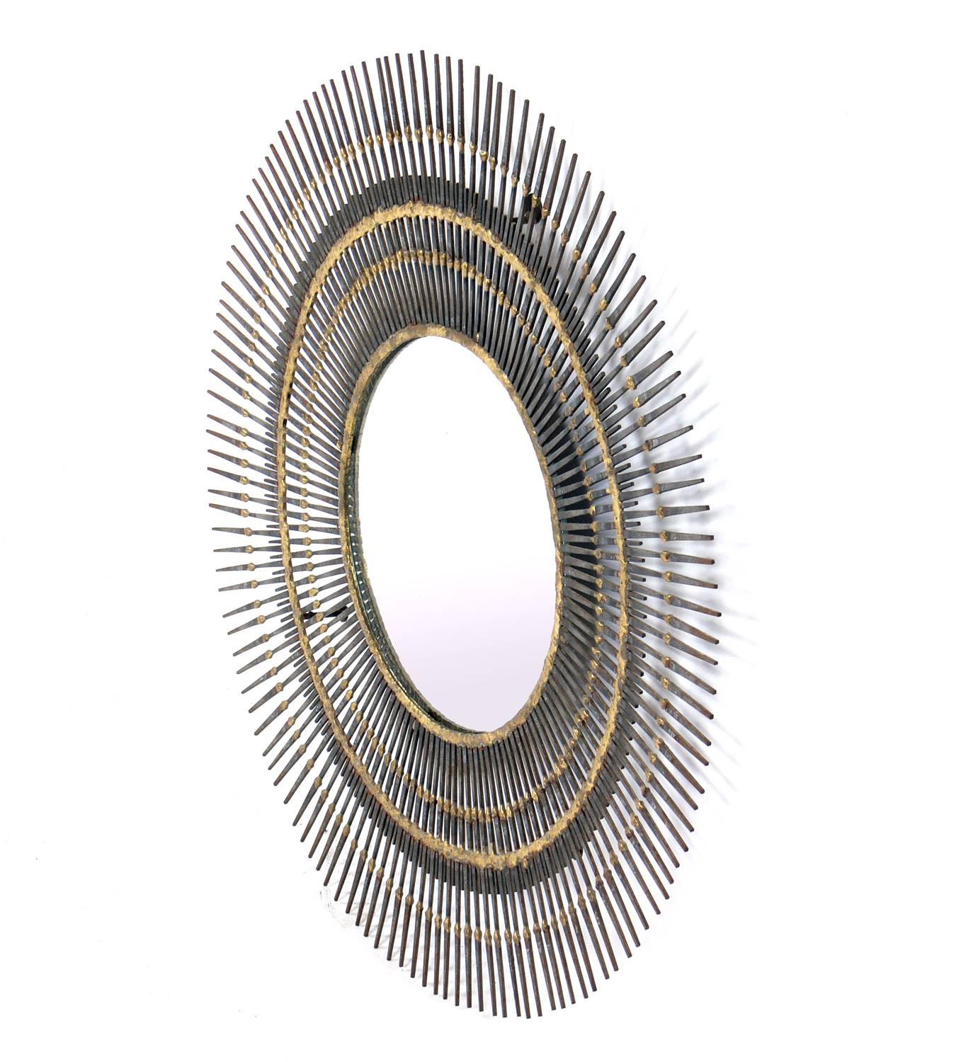 Sculptural sunburst nail mirror, American, circa 1960s. Handmade with welded patinated nails. Overall diameter is 24.5 inches, diameter of mirror is inches. Retains warm original patina. Original mounting brackets on reverse.