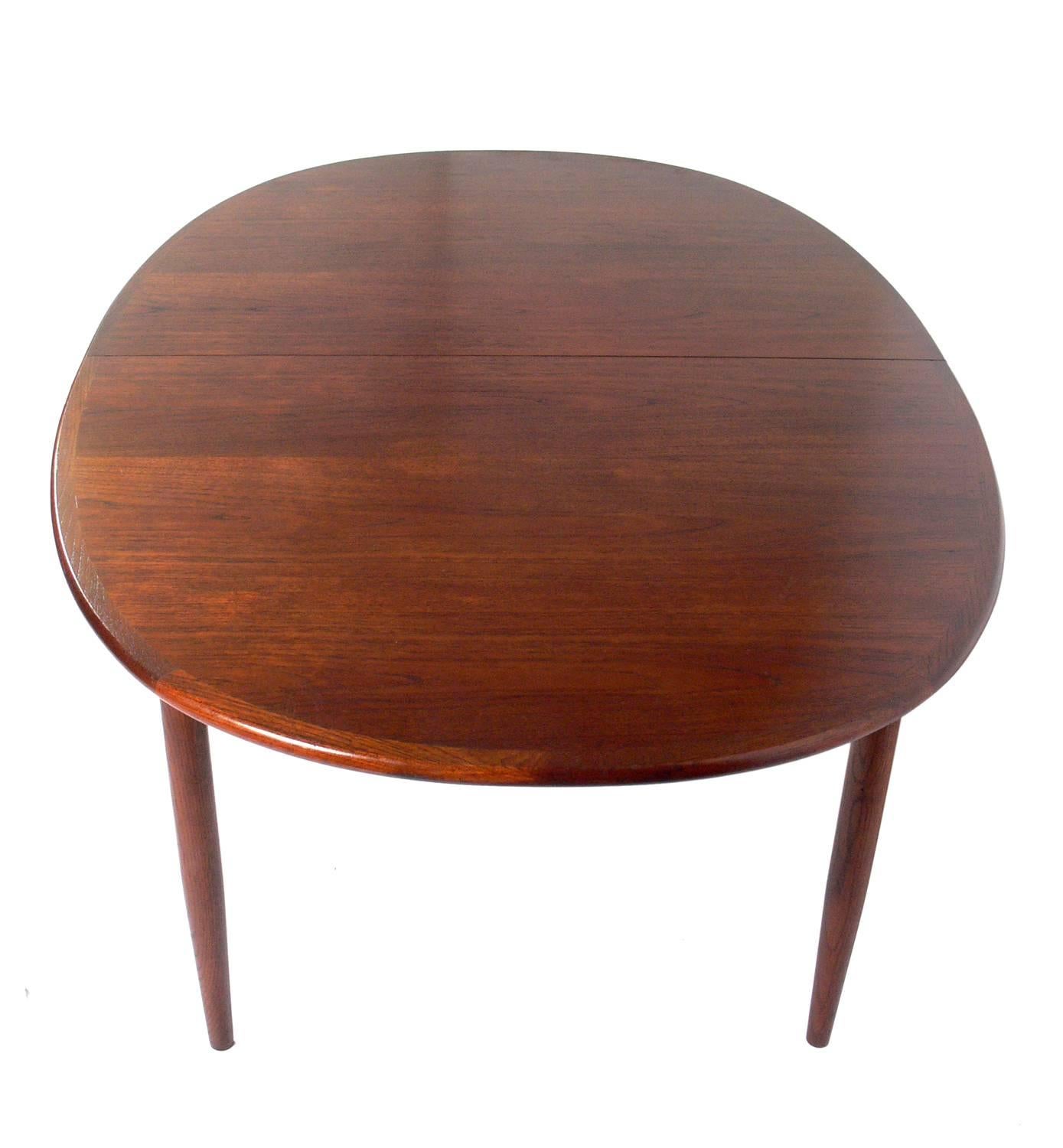 Danish modern teak dining table, Denmark, circa 1960s. The table seats six and can expand to seat twelve with all three leaves installed. It measures an impressive 117