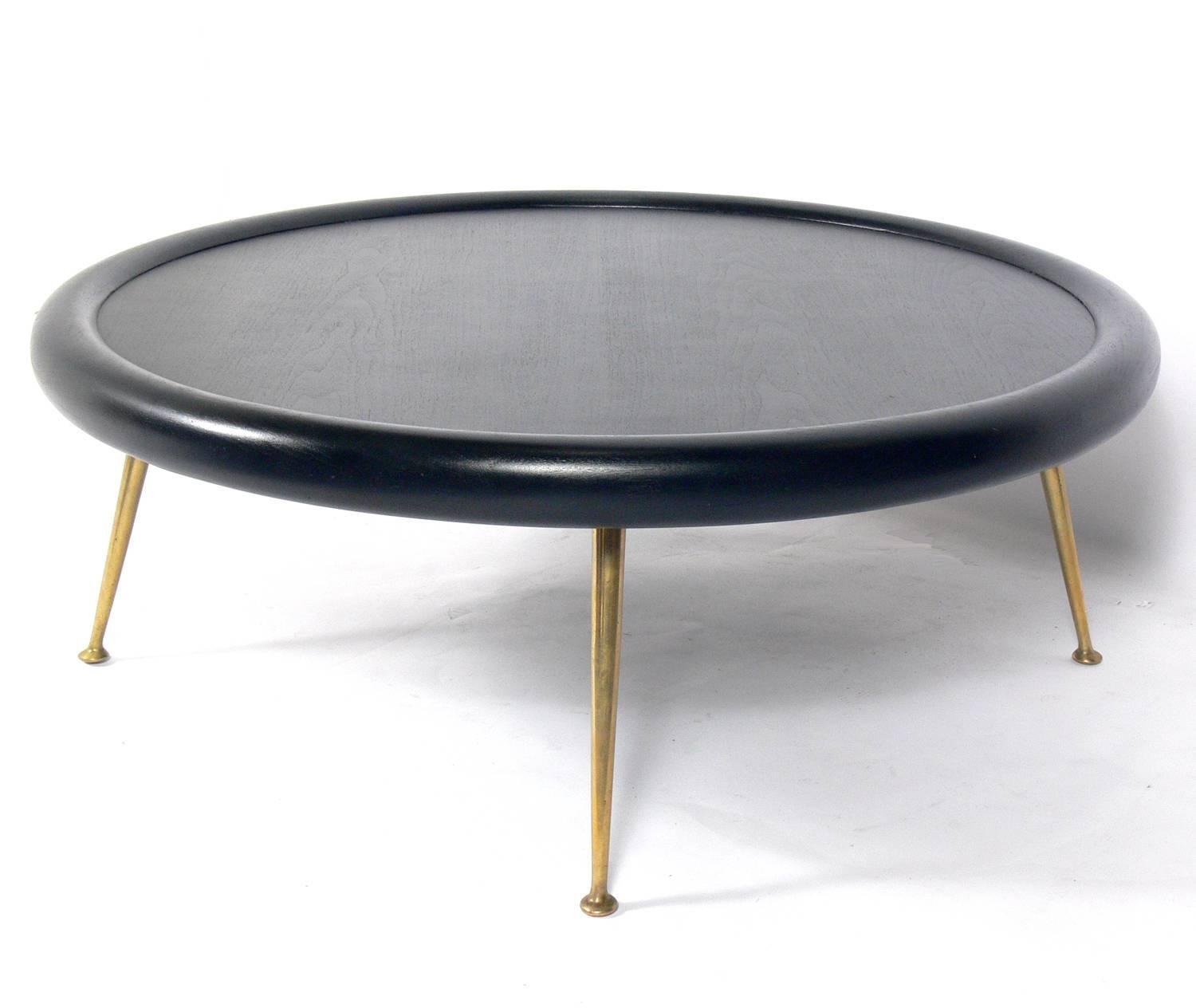 Circular coffee table, designed by T.H. Robsjohn Gibbings for Widdicomb, American, circa 1950s. It has been refinished in a black lacquer. The brass legs retain their warm original patina.