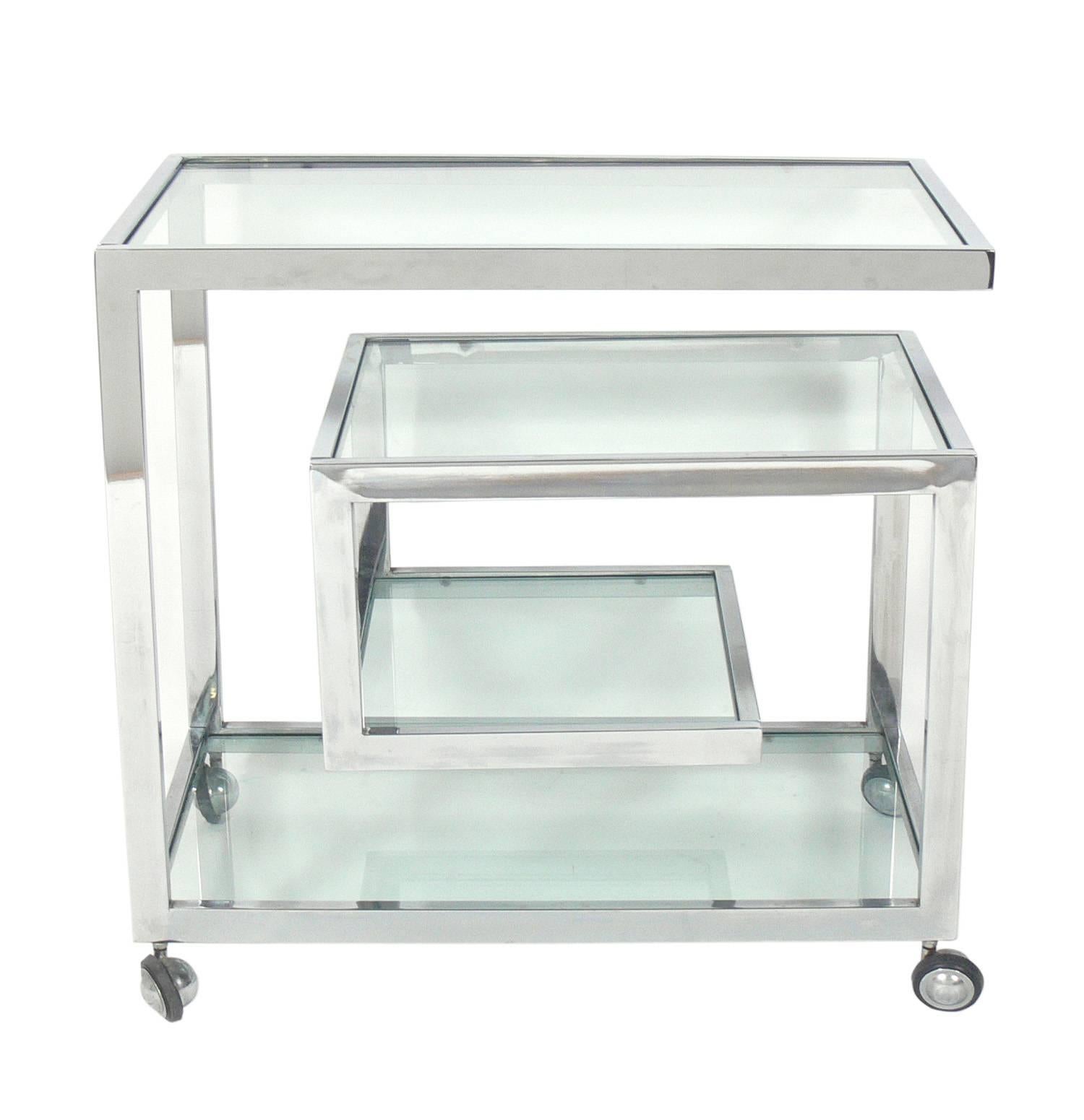 Sleek chrome bar cart, in the manner of Milo Baughman or Romeo Rega, probably Italian, circa 1960s. The glass shelves have been replaced and are free of scratches.