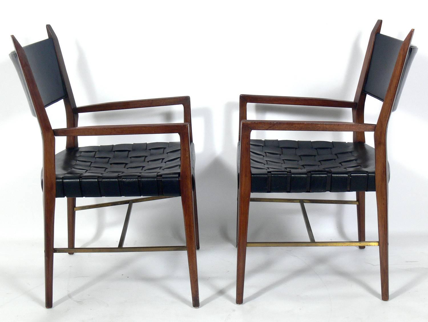 Set of four black leather, walnut, and brass dining chairs, designed by Paul McCobb, American, circa 1960s. They retain their wonderful original patina.