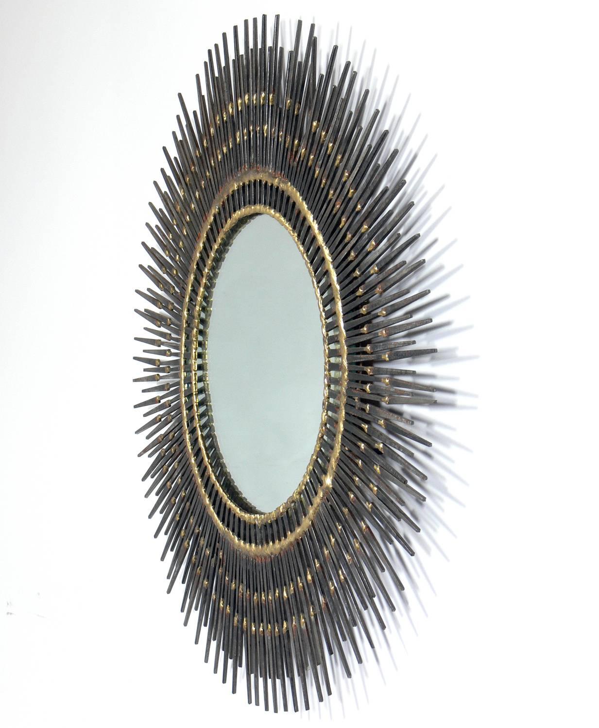 Sculptural sunburst nail mirror, American, circa 1960s. Handmade with welded patinated nails. Overall diameter is 21.5 inches, diameter of mirror is inches. Retains warm original patina.