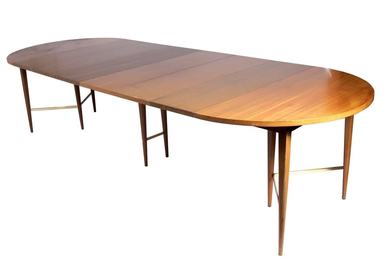 Modernist dining table, designed by Paul McCobb for Directional, circa 1950s. It expands from a perfect circle that seats four, to a large oval that can seat up to twelve guests. The table measures an impressive 120