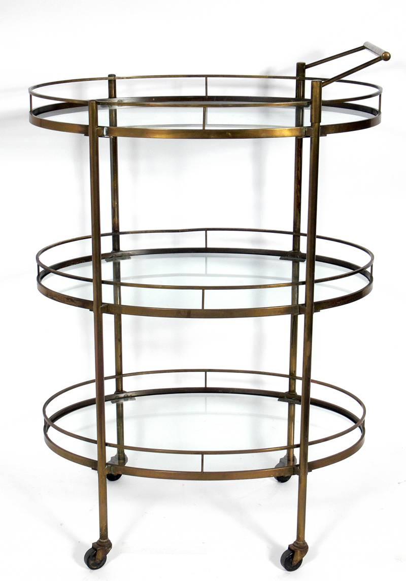 Modern three-tier brass bar or serving cart, American, circa 1950s. It retains the original warm, distressed patina to the brass.