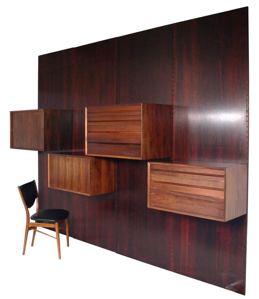Danish modern rosewood wall unit by Poul Cadovius, Denmark, circa 1960s. This piece is completely adjustable and any of the case pieces can be installed anywhere up and down the wall-mounted panels. This piece is a versatile size and can be used as