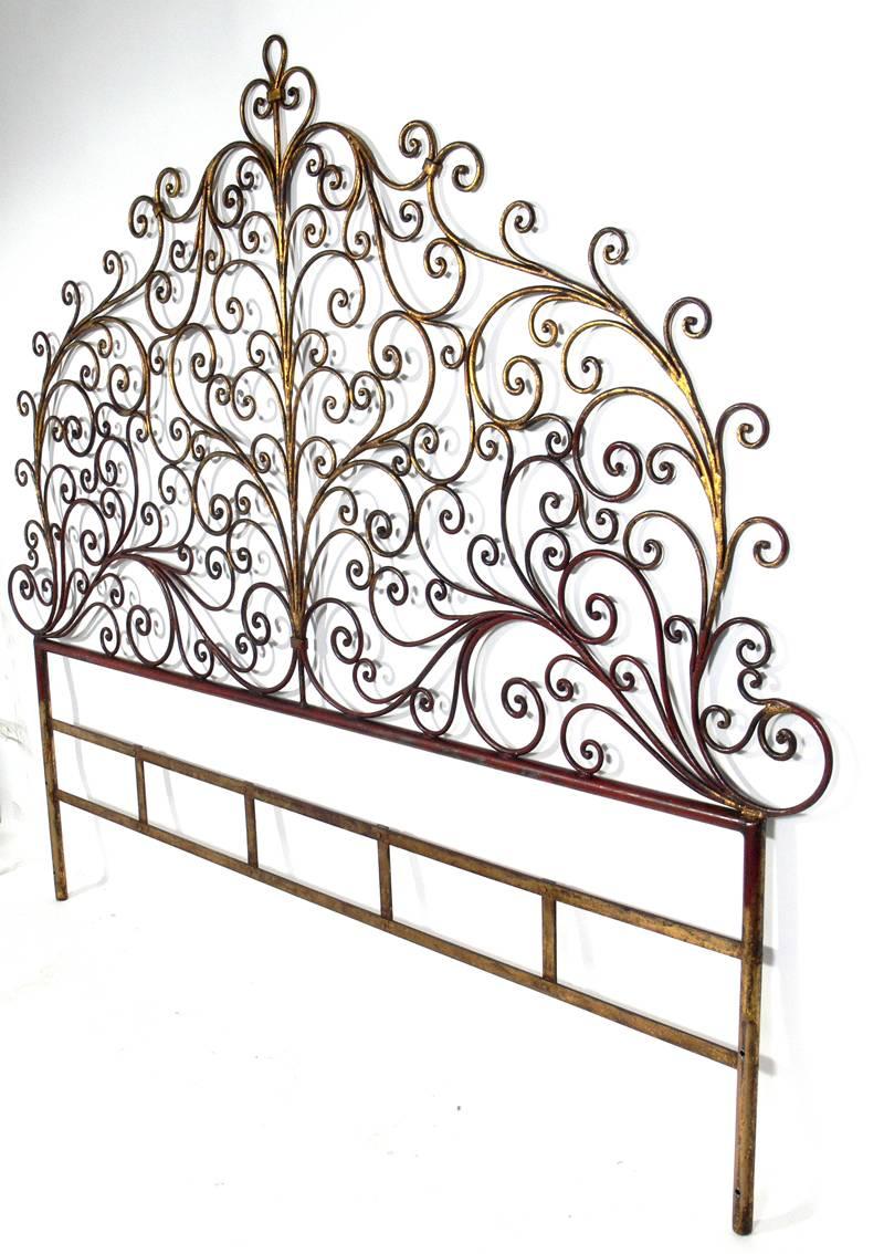Glamorous gilt metal headboard, Italian, circa 1950s. It retains its original gilt finish with a wonderful patina with some overall wear to the gold leafed metal frame, exposing the Chinese red underlayer or bole.