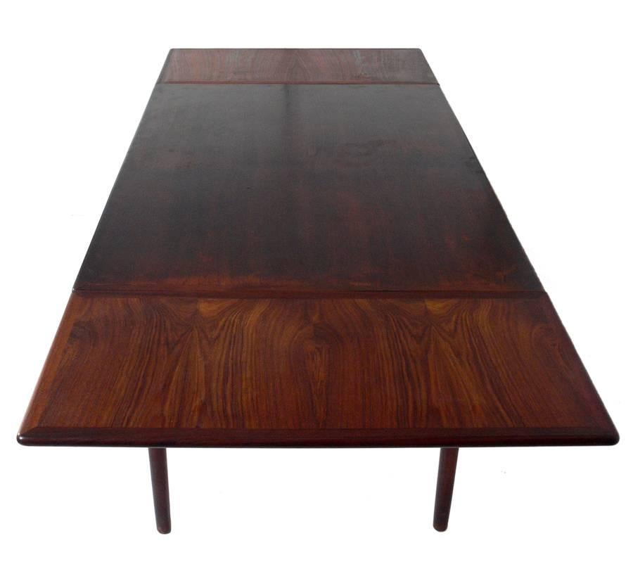 Danish modern rosewood dining table, Denmark, circa 1960s. Beautiful graining to the rosewood. This table is currently being refinished, and when completed, the table and the leaves will match.