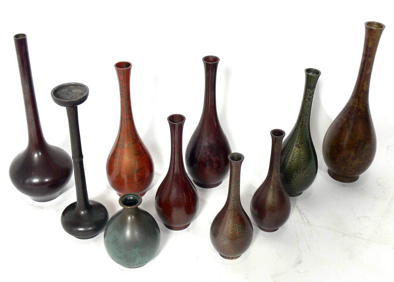 Collection of ten Japanese bronze vases, Japan, 20th century. They all exhibit sculptural forms and have a wide range of patinas from deep browns and reds to warty verdigris. From left to right, the vases measure in height: 11