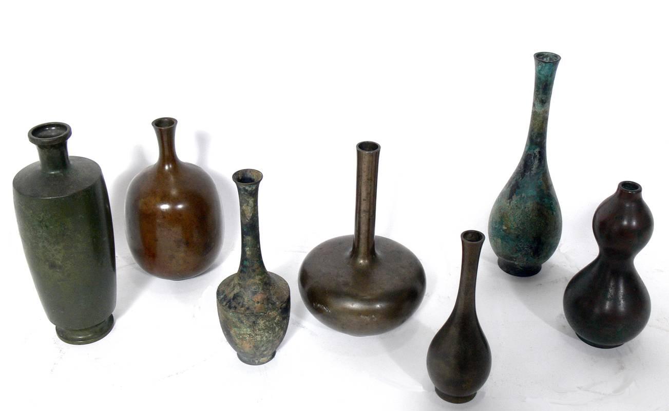 Collection of seven Japanese bronze vases, Japan, 20th century. They all exhibit sculptural forms and have a wide range of patinas from deep browns and reds to warty verdigris. From left to right the vases measure in height: 9.5