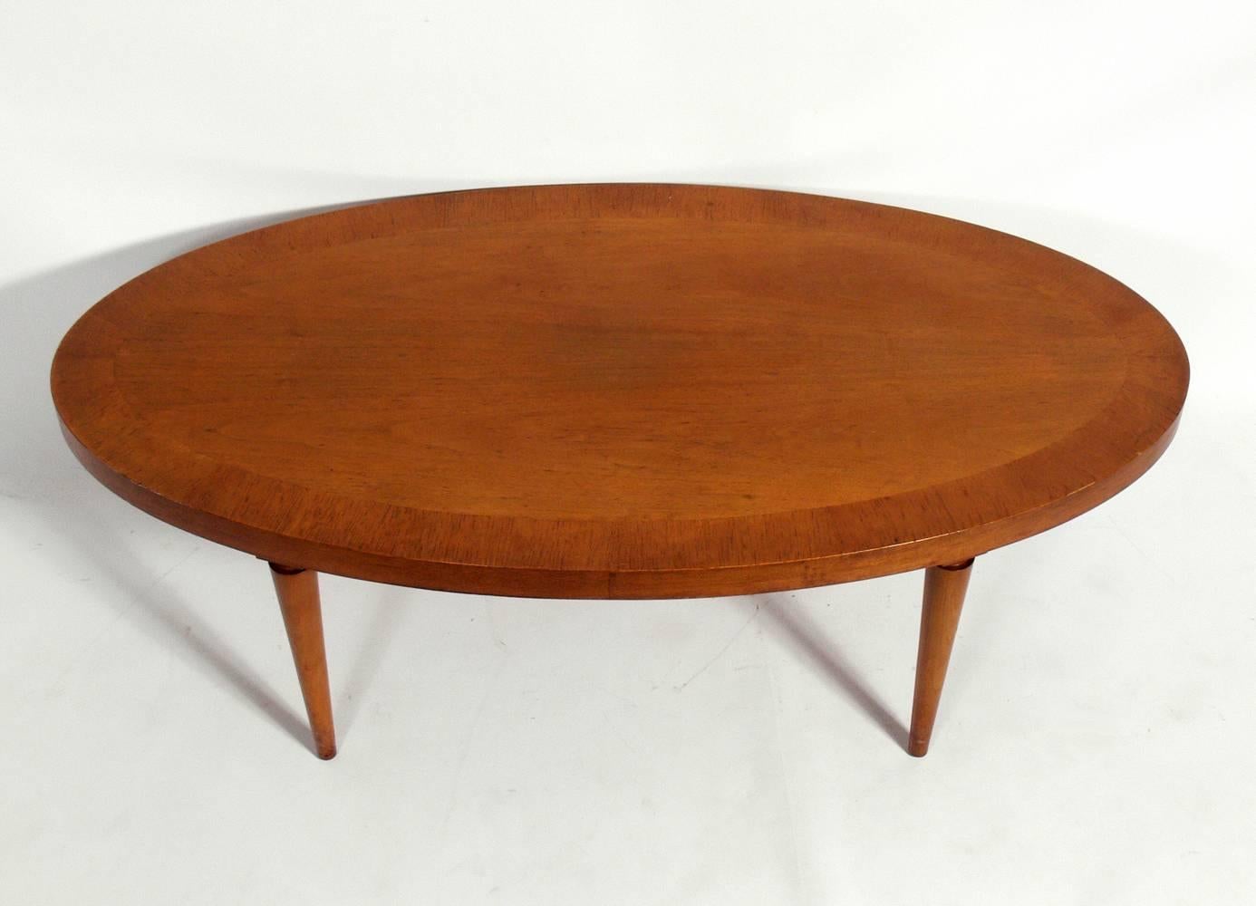 Elegant oval coffee table, designed by T.H. Robsjohn-Gibbings for Widdicomb, American, circa 1950s. This piece is currently being refinished and can be completed in your choice of color. The price noted below includes refinishing in your choice of