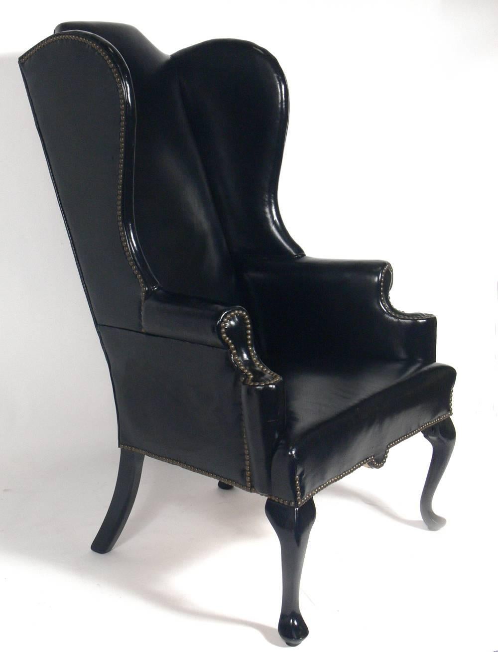 Perfectly patinated black leather wing back lounge chair, American, circa 1950s. The original black leather upholstery is perfectly broken in, with overall aged patina. The brass nailhead trim also exhibits wonderful patina. The wooden legs have