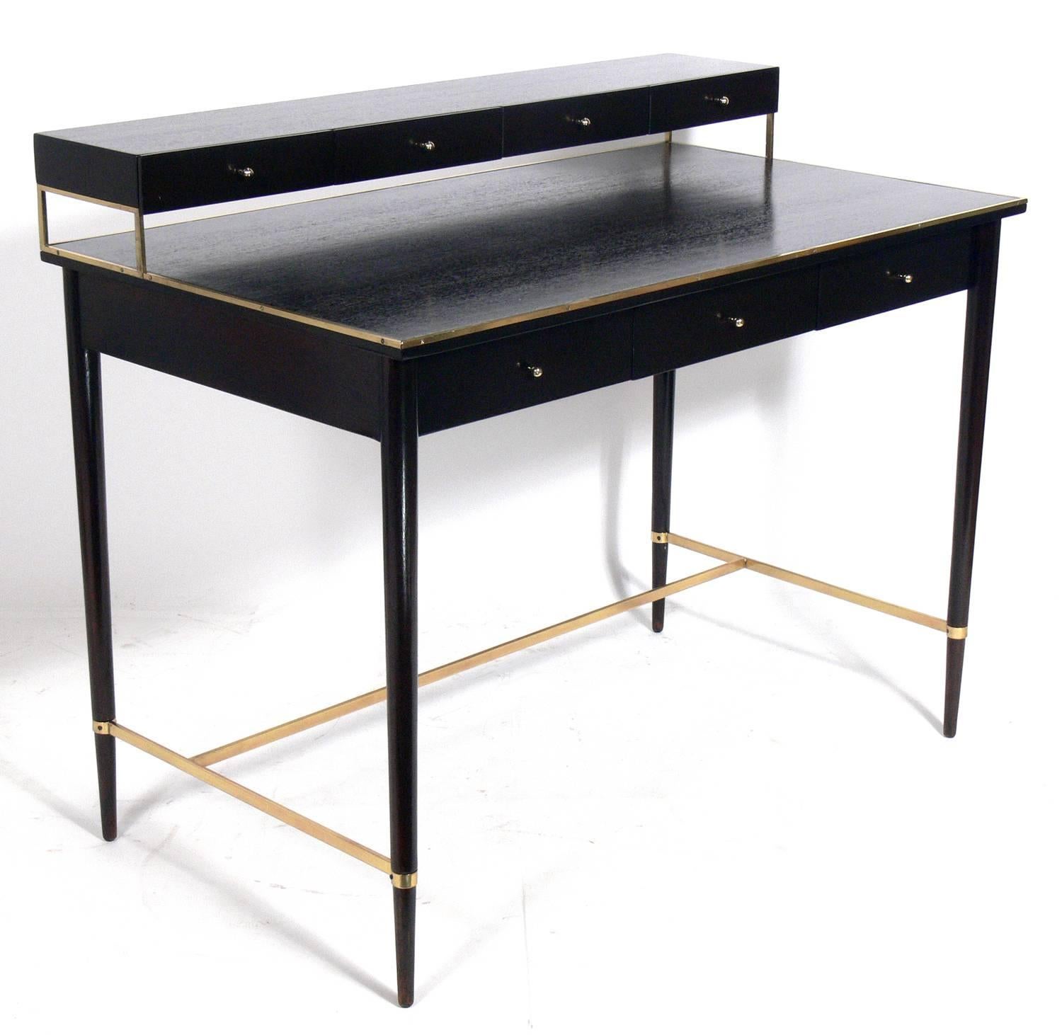 Clean lined Mid-Century Modern desk and chair, designed by Paul McCobb, American, circa 1950s. They have been completely restored in an ultra-deep brown finish with the brass elements polished and lacquered. The chair seat has been reupholstered in