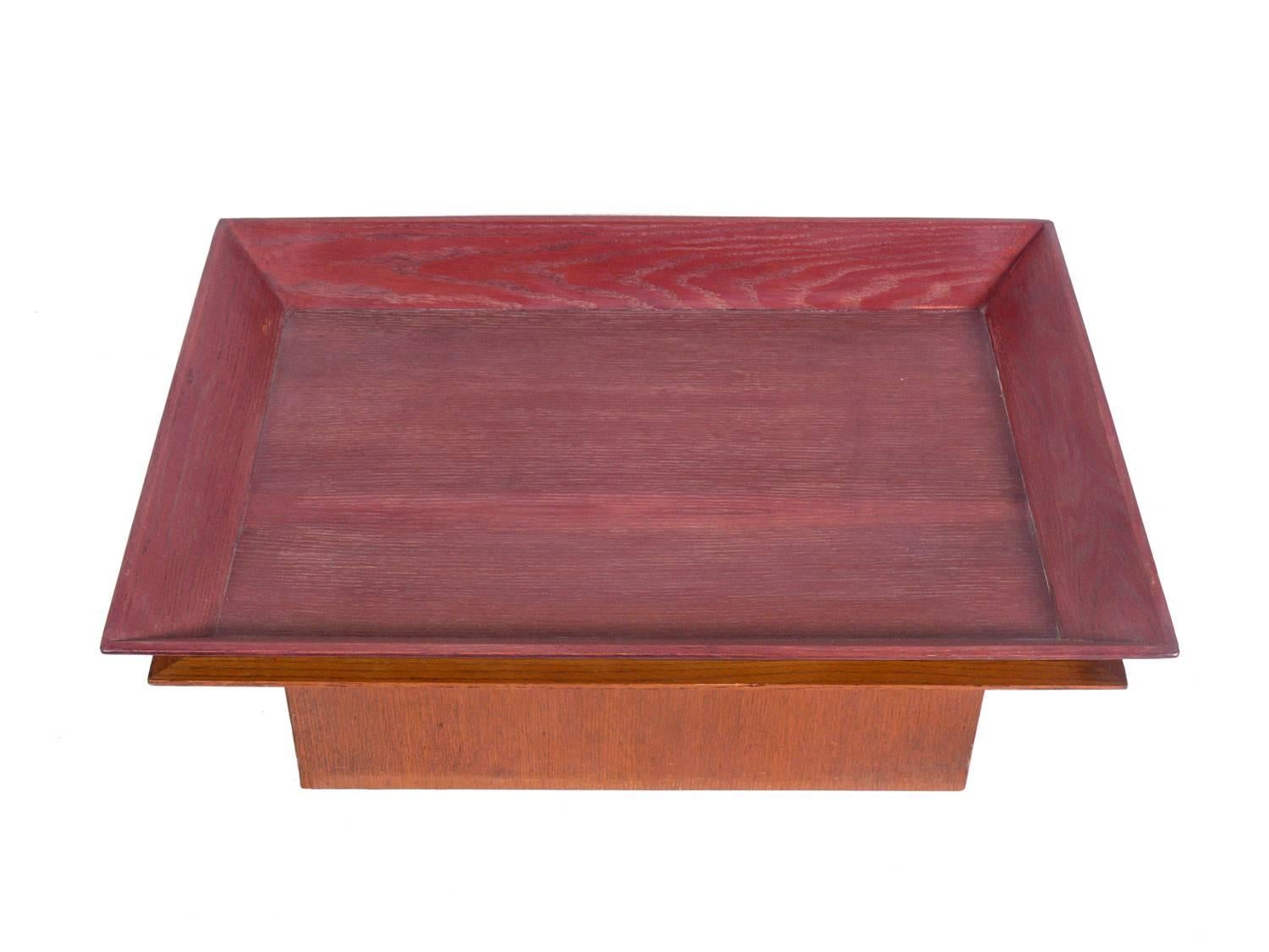Skyscraper form coffee table with removable tray, in the manner of Paul Frankl, American, circa 1930s. It is executed in oak with the bottom portion finished in a natural color and the tray top executed in an Asian red color.