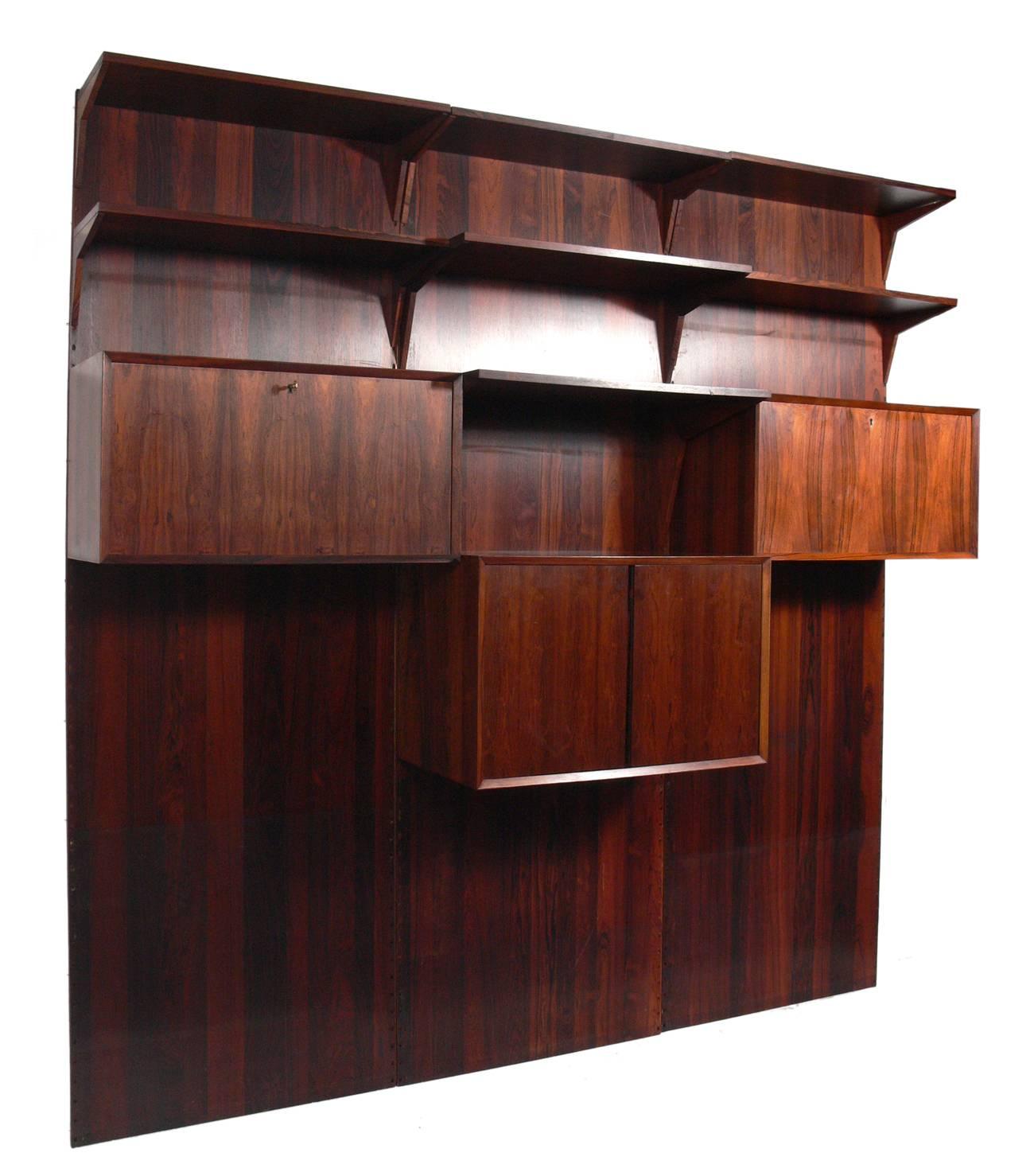 Danish modern rosewood wall unit by Poul Cadovius, Denmark, circa 1960s. Beautiful graining to the rosewood. This piece is completely adjustable and any of the case pieces or shelves can be installed anywhere up and down the wall-mounted panels.
