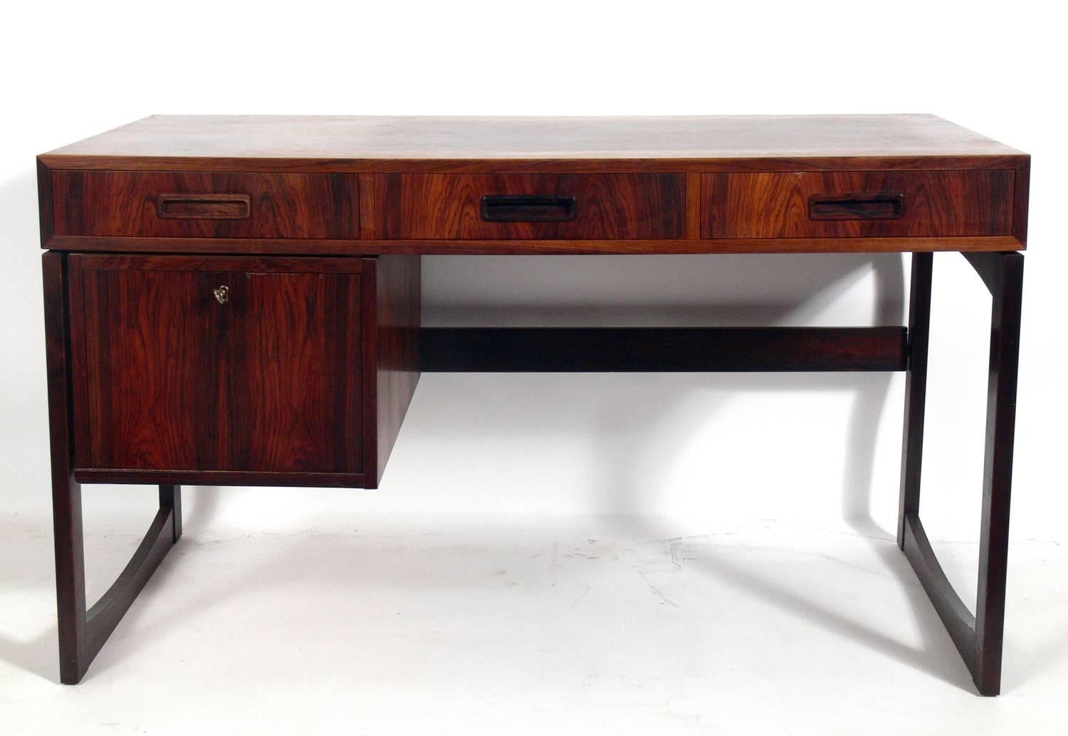 Danish modern rosewood desk, Denmark, circa 1960s. This piece is a versatile size and has a lot of storage for a small footprint. There are three deep drawers at the top and one large file drawer at the lower left. This piece is currently being