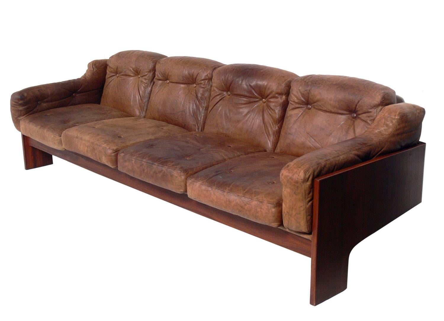 Sculptural Danish modern rosewood and leather sofa, Denmark, circa 1960s. It retains it's original natural color leather cushions. If you prefer, we can reupholster the cushions in your fabric for an additional charge.