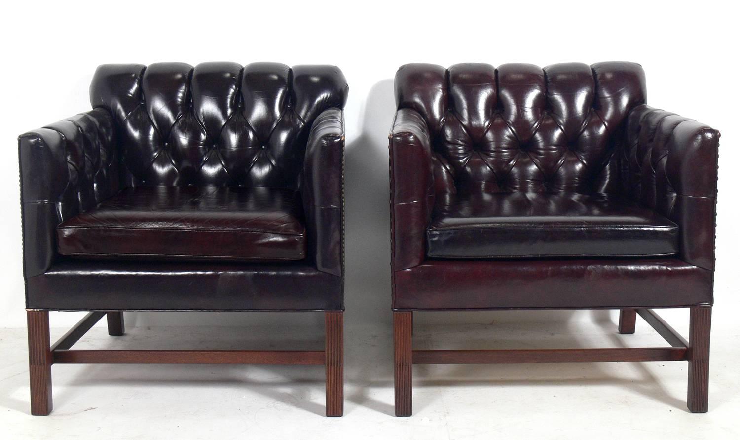 Pair of tufted cabernet color leather lounge chairs, made by the Kittinger Company, American, circa 1950s. Very comfortable pair of club chairs. They retain their wonderful original patina to the leather and brass nailheads and the mahogany wood