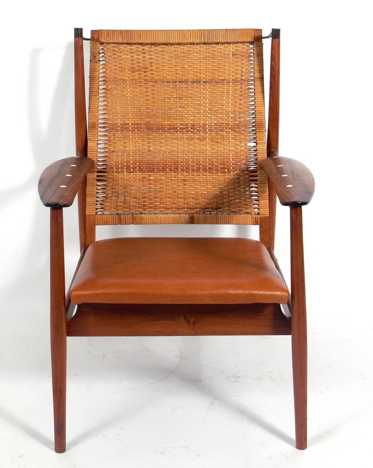 Danish modern lounge chair in the manner of Finn Juhl's NV-55 chair, Denmark, circa 1960s. Constructed of a beautiful mix of materials including rosewood inlaid arms, teak, brass, woven cane and cognac color leather. Retains warm original patina.