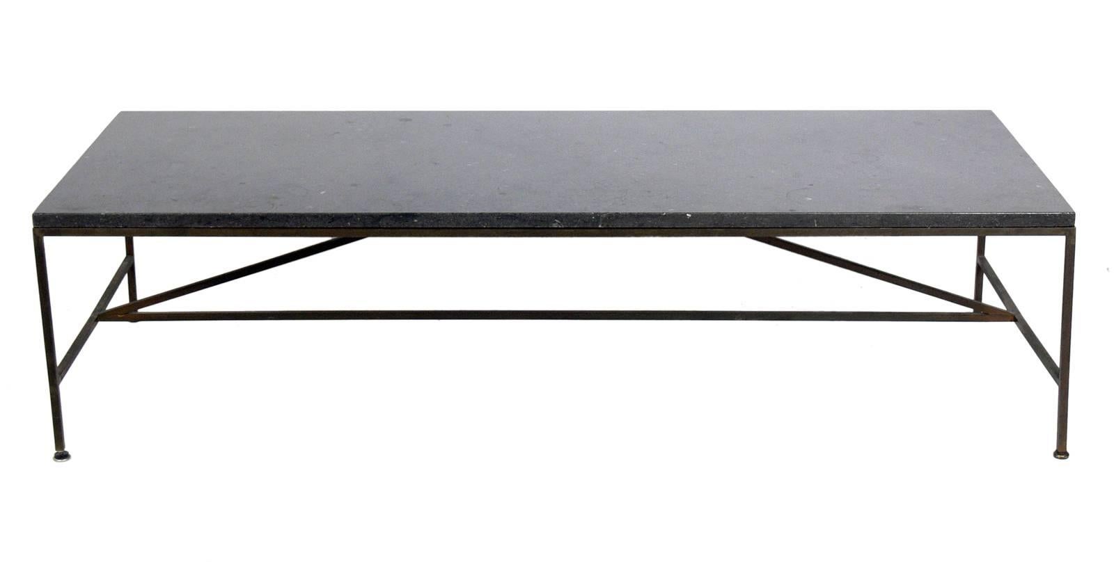 Marble-top coffee table designed by Paul McCobb for Calvin, American, circa 1950s. The marble top is a deep charcoal gray color, almost black, and the brass or brass plated metal base retains it's warm original patina.