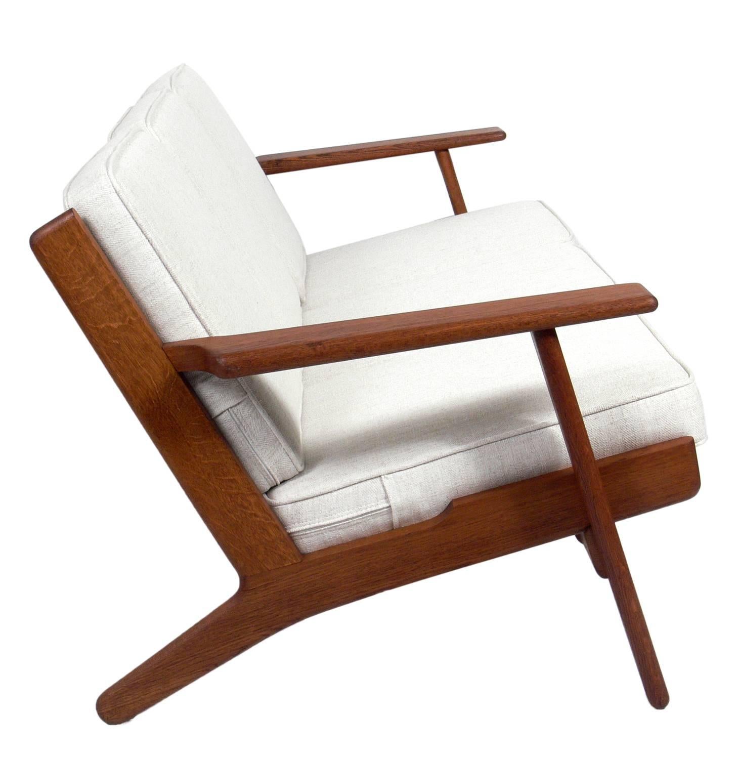 Danish Modern oak sofa, designed by Hans Wegner for GETAMA, Denmark, circa 1960s. The oak frame retains it's warm original patina and the cushions have been reupholstered in an ivory color herringbone upholstery.