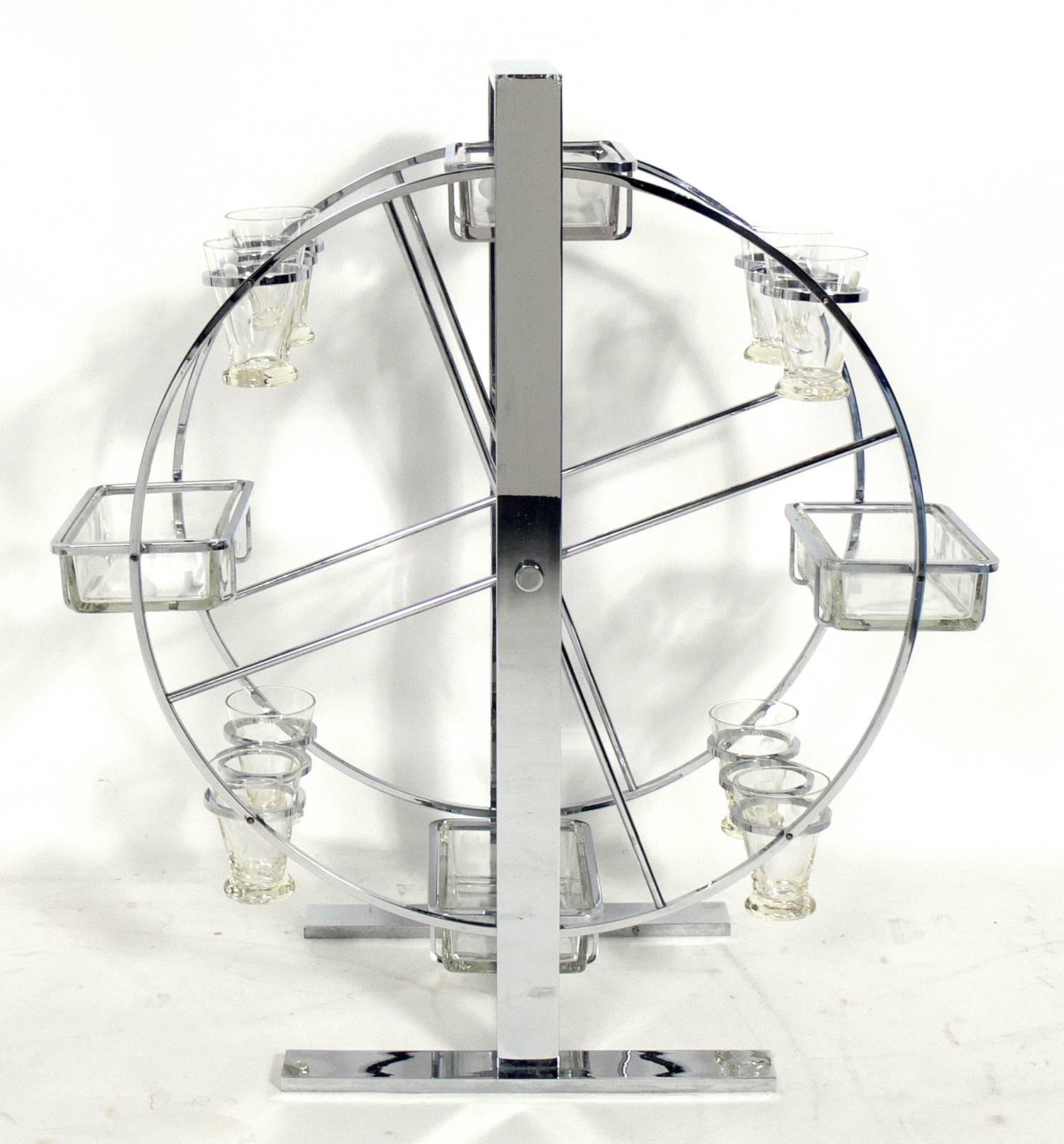 Art Deco Ferris wheel cocktail server, attributed to Norman Bel Geddes, American, circa 1930s. This piece was used to serve cocktails and snacks. It has been polished and is ready to use. Consist of four glass snack serving trays and eight cocktail