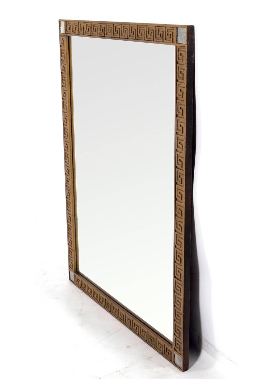 Elegant Greek key mirror, American, circa 1940s. It is constructed of gold painted wood frame with inset antiqued mirrors at the corners and mirrored glass in the center. Retains its warm original patina to the frame and mirror.