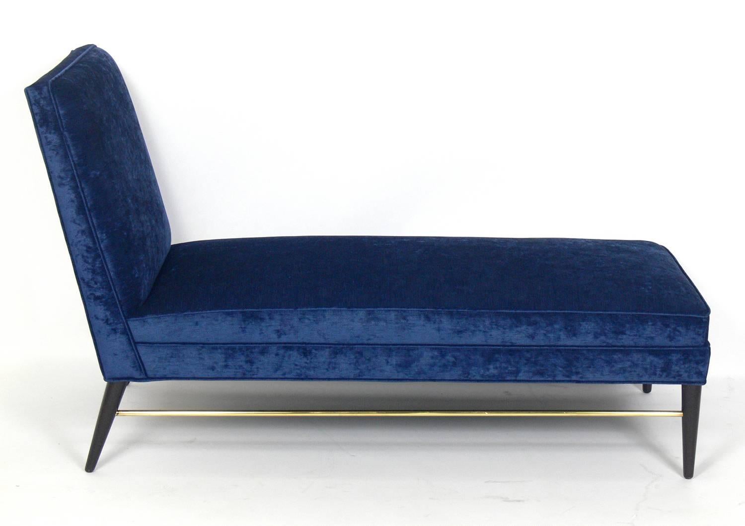 Modern chaise longue designed by Paul McCobb, American, circa 1950s. It has been completely restored in a velvety indigo blue fabric with the wood legs finished in an ultra-deep brown lacquer and the brass stretcher hand polished.