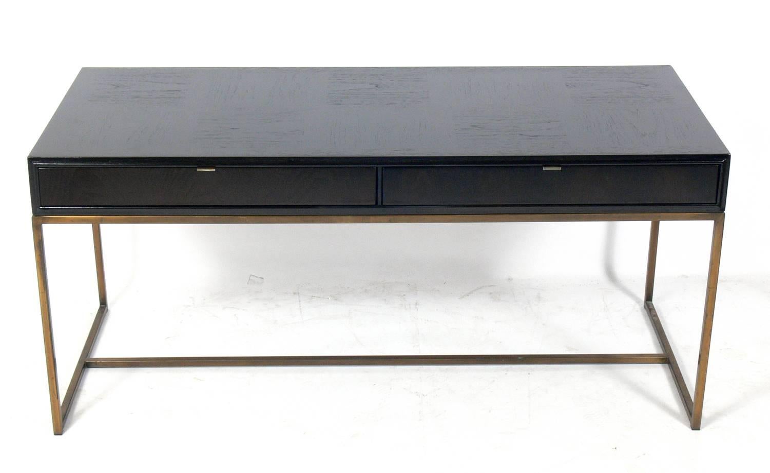 Clean lined Mid-Century Modern desk, American, circa 1960s. It has been refinished in an ultra deep brown color lacquer. The brass color metal base and hardware retain their warm original patina. It is a versatile size and can be used as a desk,