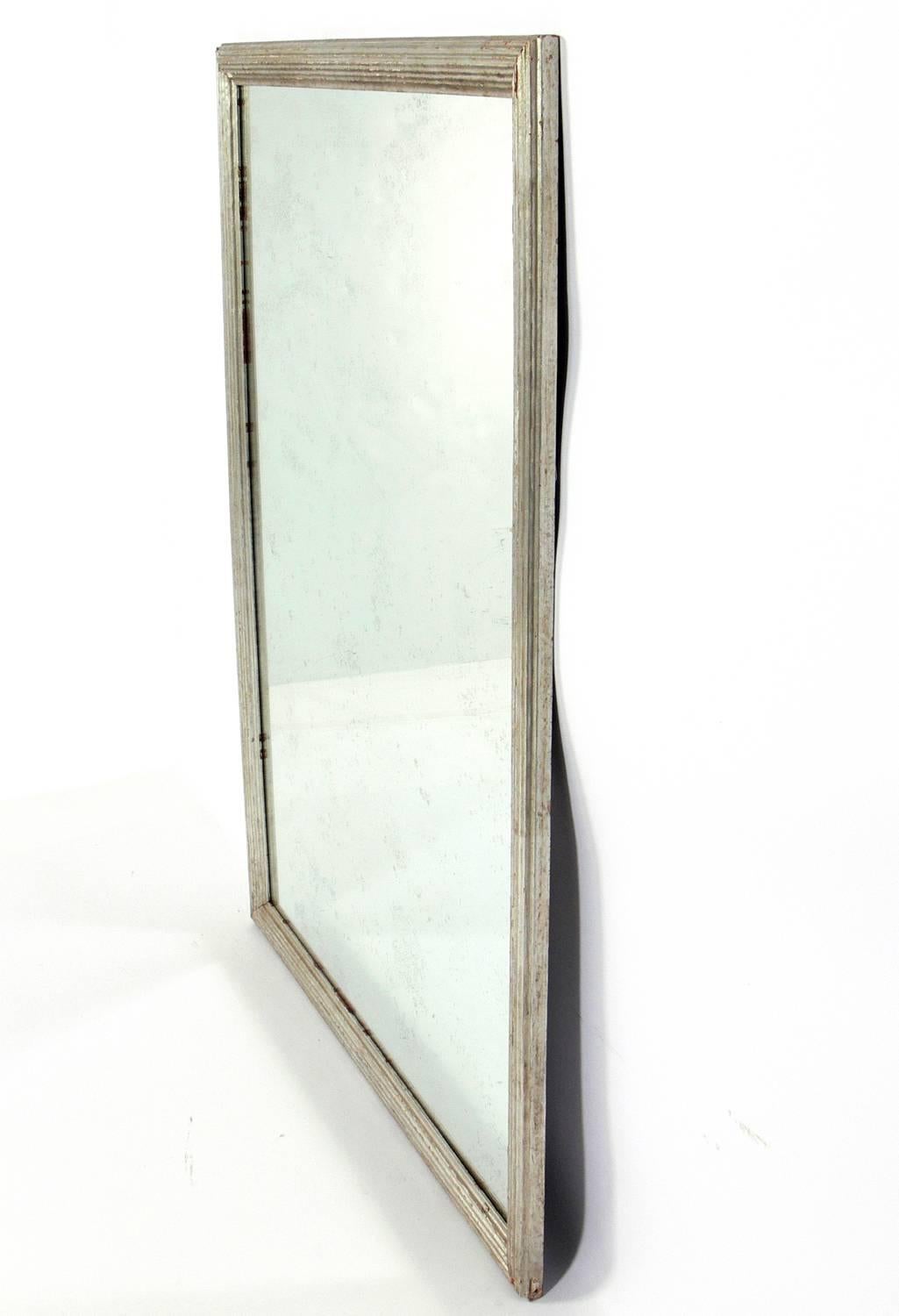 Silver finished antiqued mirror, American, circa 1930s. Retains original distressed silver finish over the gesso and wood and fitted with an antiqued mirror.
