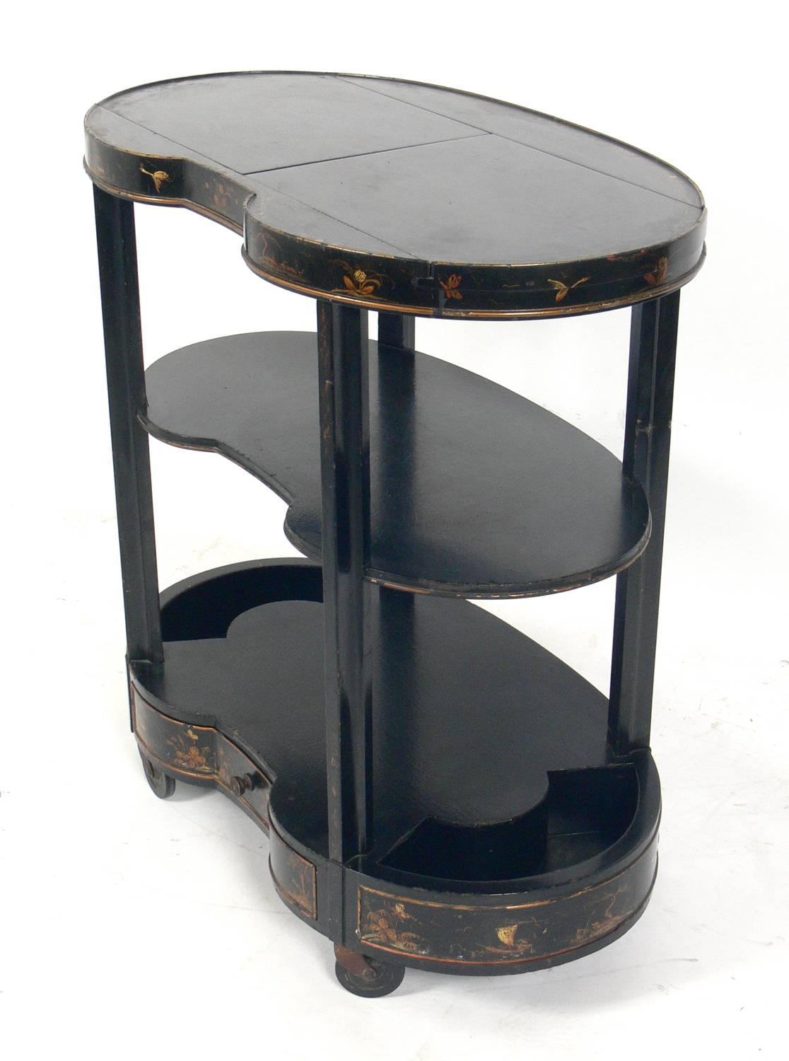 Elegant Chinoiserie bar cart, American, circa 1940s. Retains original black lacquer finish with subtle chinoiserie decoration and original copper clad serving area that is revealed when the sliding top opens.
