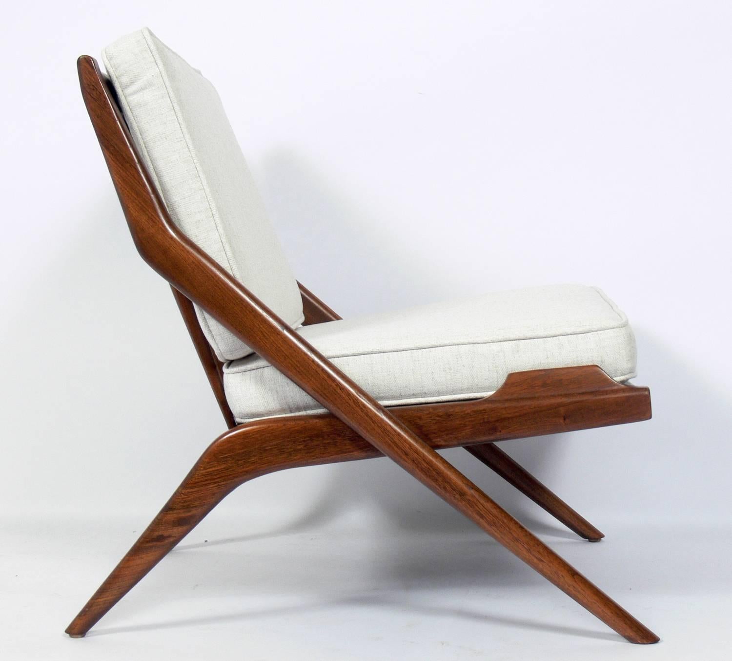 Danish modern scissor lounge chair, in the manner of Folke Ohlsson, circa 1960s. Refinished and reupholstered in an ivory color herringbone upholstery.