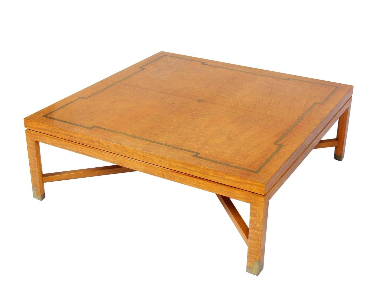 Elegant coffee table, custom-made by Tommi Parzinger Originals, circa 1950s. The beautifully grained maple is inlaid with brass on the tabletop and the sabots. This large-scale table measures an impressive 42