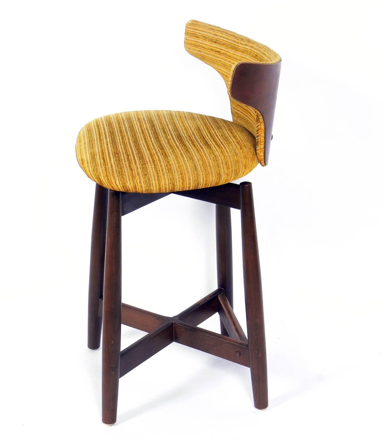 Set of three curvaceous low slung walnut modern bar stools, probably Italian, circa 1950s. We have a total of five of these bar stools available. The price noted below is for three stools. They are currently being refinished and reupholstered. They