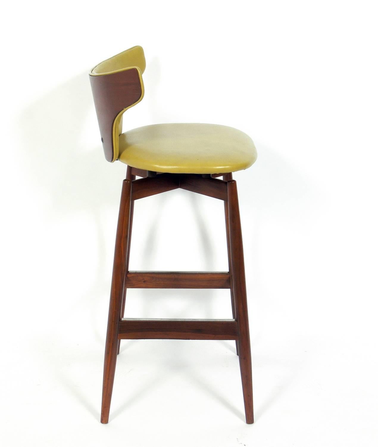 Set of three curvaceous walnut modern bar stools, probably Italian, circa 1950s. They retain their original vinyl upholstery. If you prefer, we can reupholster them in your fabric for an additional charge.
 