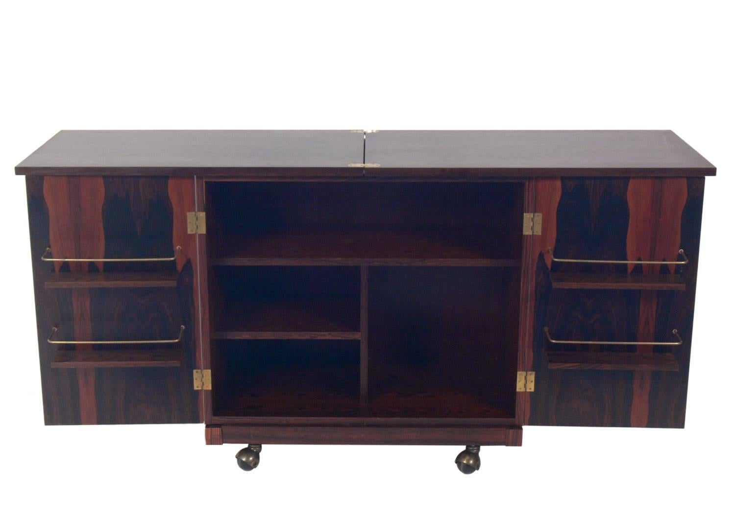 Danish Modern rosewood bar cart, designed by Torbjorn Afdal for Bruksbo, Norway, circa 1960s. The doors open to reveal a voluminous amount of storage, and the top flips open to offer a larger serving or work space. Retains warm original finish.