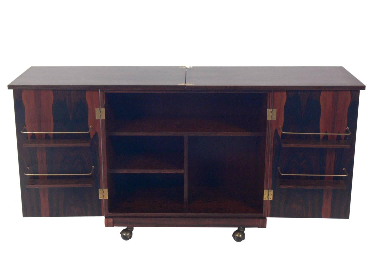 Danish Modern rosewood bar cart, designed by Torbjorn Afdal for Bruksbo, Norway, circa 1960s. The doors open to reveal a voluminous amount of storage, and the top flips open to offer a larger serving or work space. Retains warm original finish.
