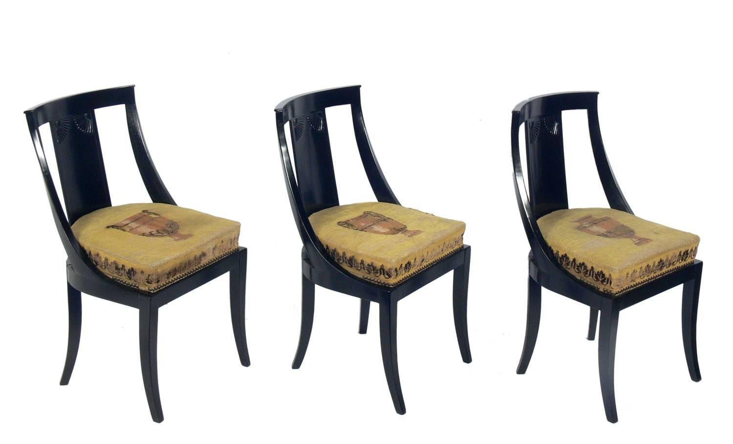 Set of six Art Deco dining chairs, French, circa 1920s. They have been refinished in a black lacquer finish and retain their original neoclassical needlepoint seats. The seats have considerable wear, and can be used as is, if you appreciate the