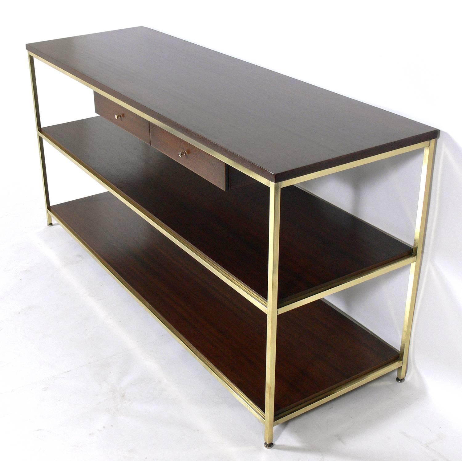 Paul McCobb Console Table, American, circa 1950s. This piece has been completely restored. Refinished in a medium brown walnut, and brass frame polished and lacquered. It is a versatile size and can be used as a console or sofa table, media center,