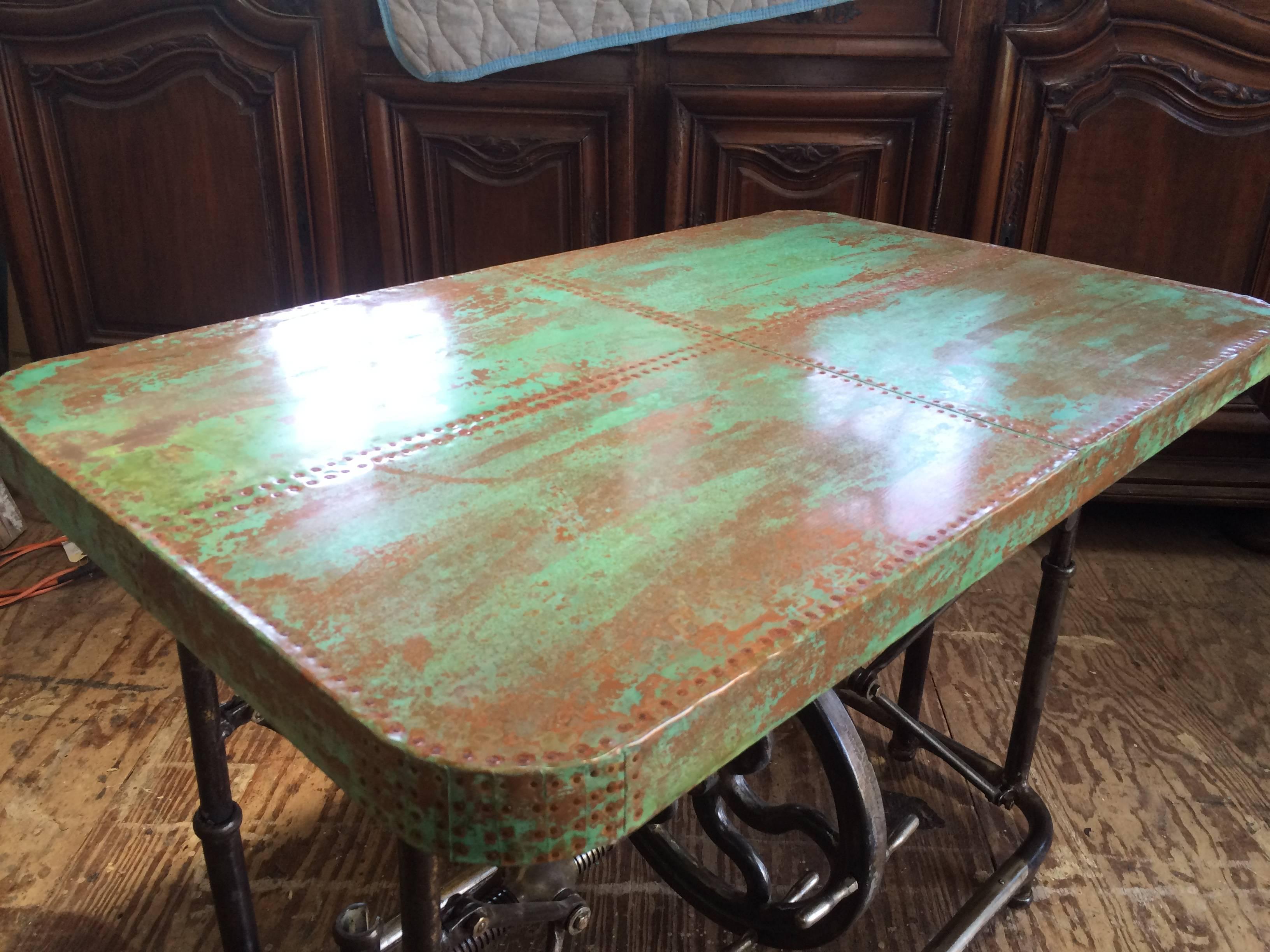 Unusual Industrial steel table with patinated copper top. Made of steel with a geared and fly wheeled mechanism to raise and lower the top. This can be used as a coffee table, dining table, bar, or sofa table. Mechanical base made in Pennsylvania,