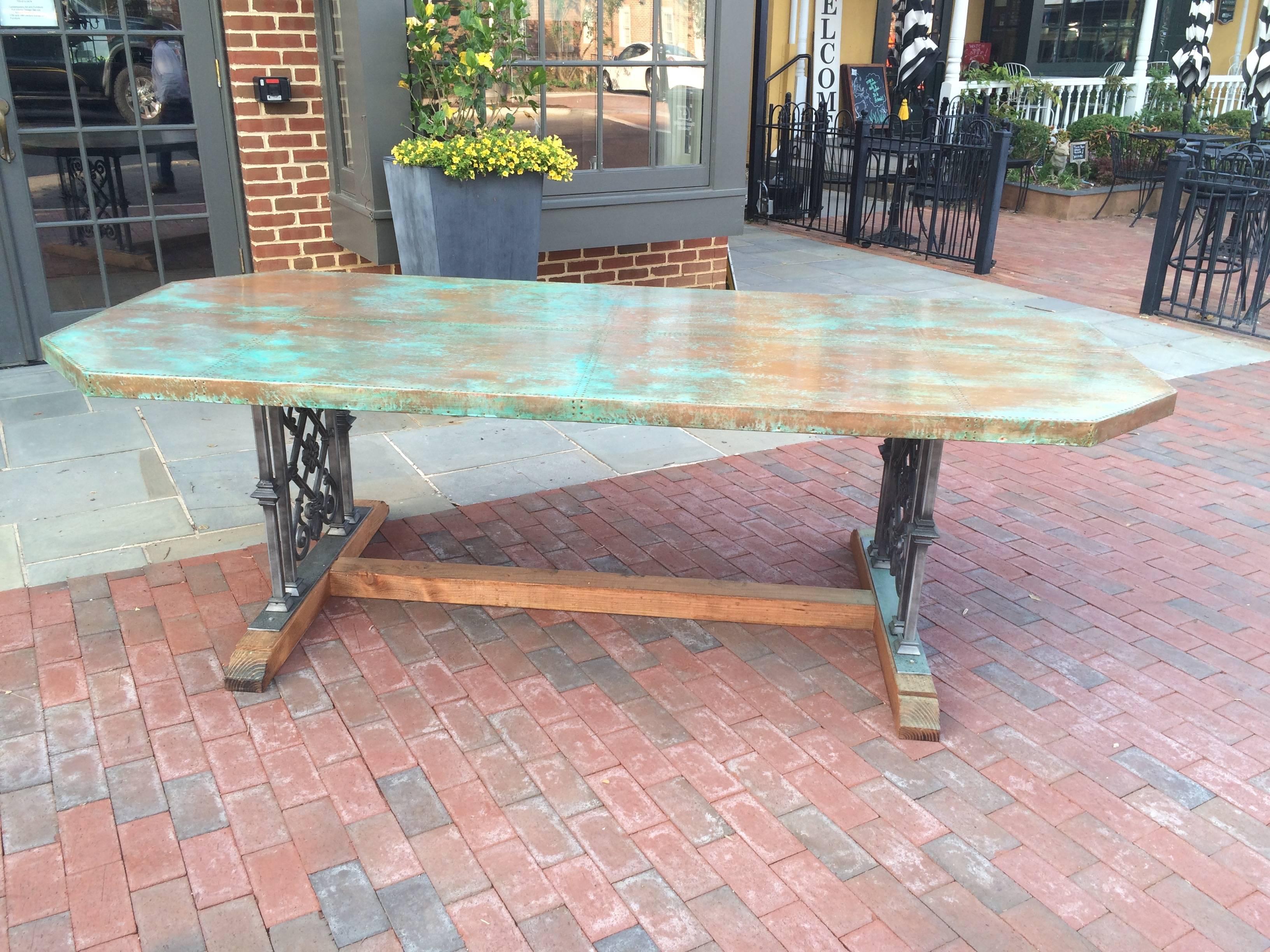Custom designed copper dining table. Top paneled in copper with a green “verdigris“ patination and 2000 hand-hammered nails. Trestle Base made of cast iron balustrade with cedar feet and central stretcher .This table is designed and custom made by