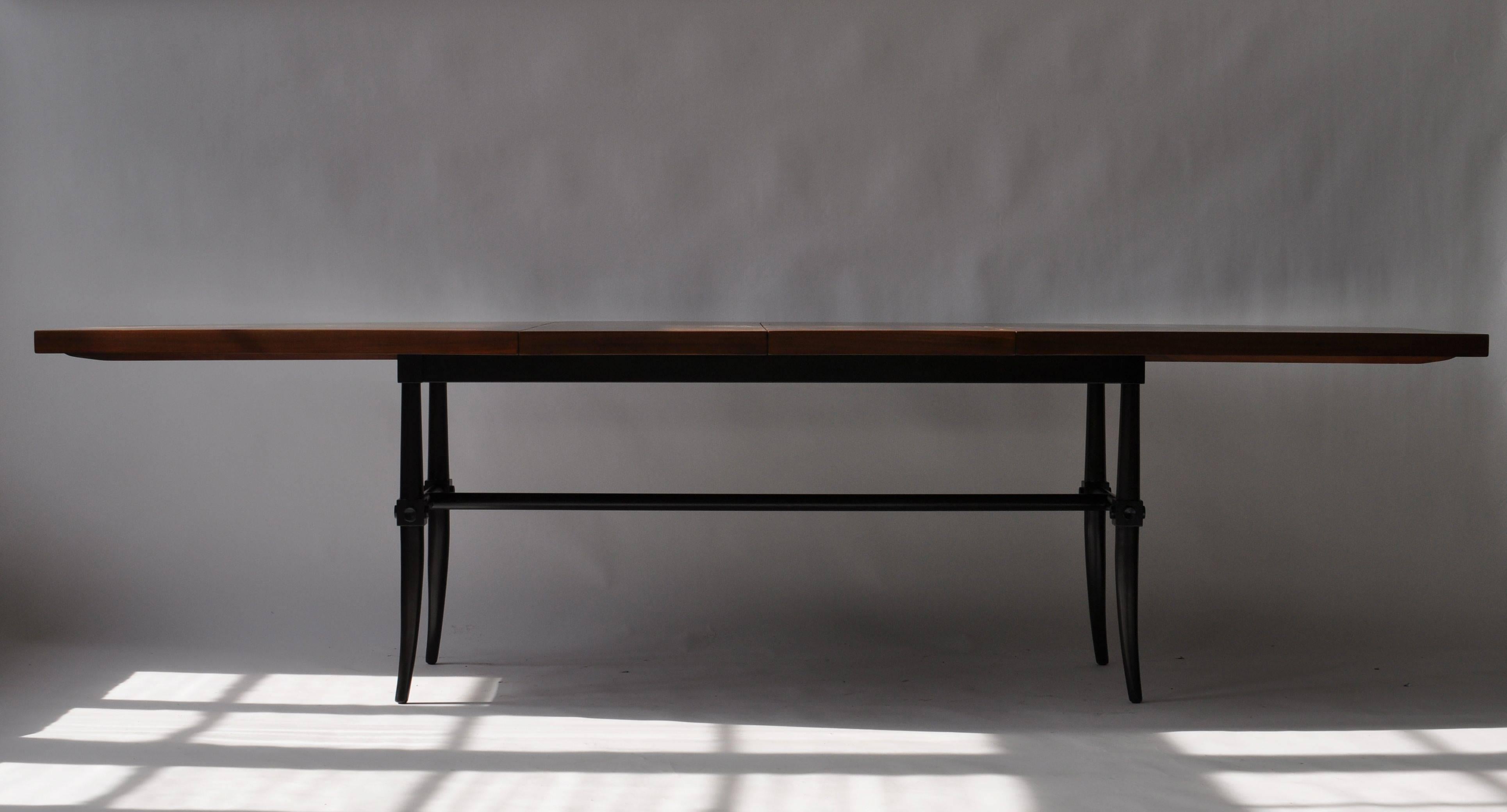 Rare dining table by Tommi Parzinger. Mahogany top with holy butterfly inlays though out. Flared sabre leg. Table measures 29 high X 44.5 inches wide in the center. The ends measure 26" wide. Table is 76 " long and has two 18 inches