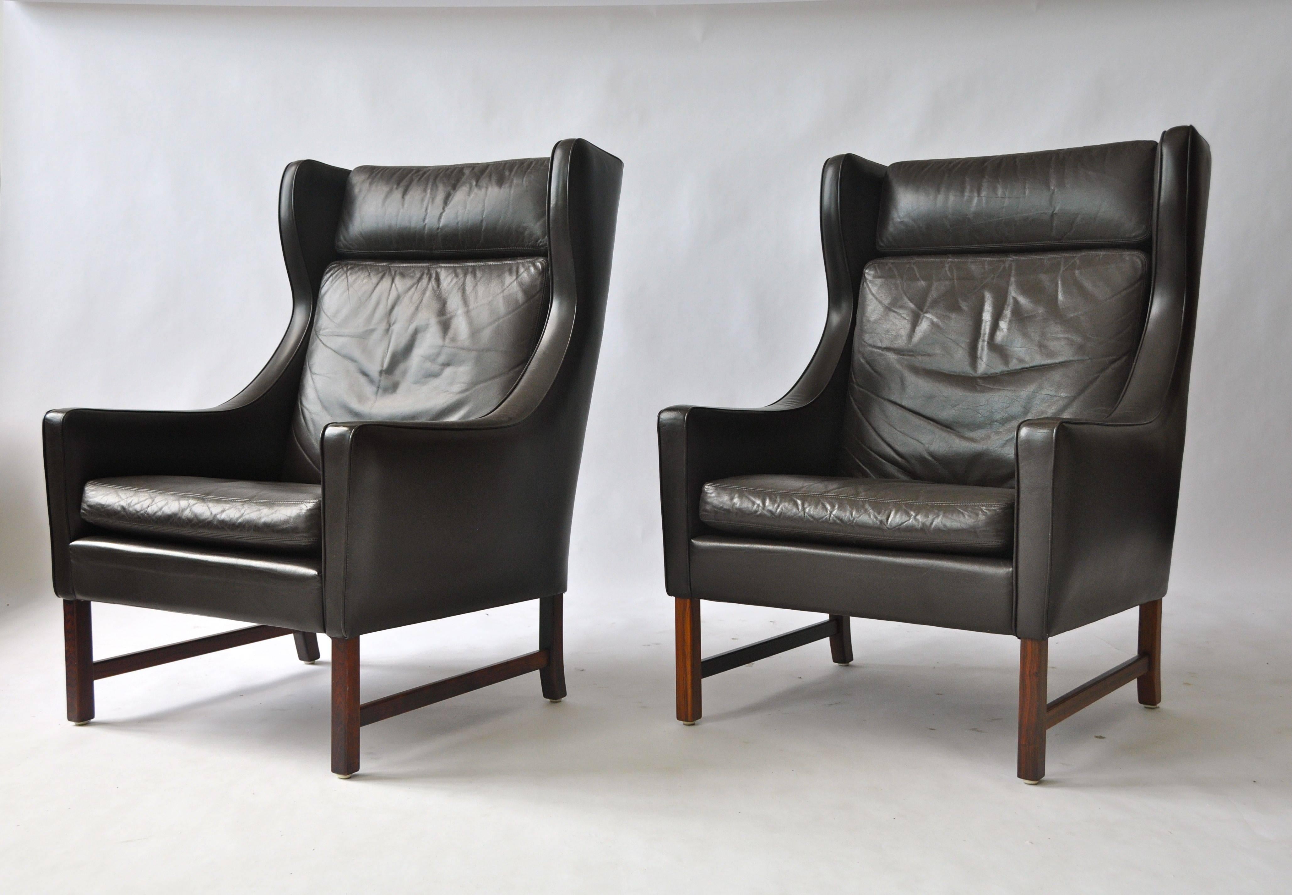 Pair of Frederik Kayser leather wing chairs. Rosewood base. Dark brown leather. Single ottoman with purchase. Produced by Vatne Møbler, Norway, model 965. Designed in 1964.
